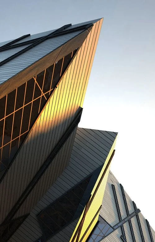 Angular metal-clad facade catching warm sunlight against a clear sky