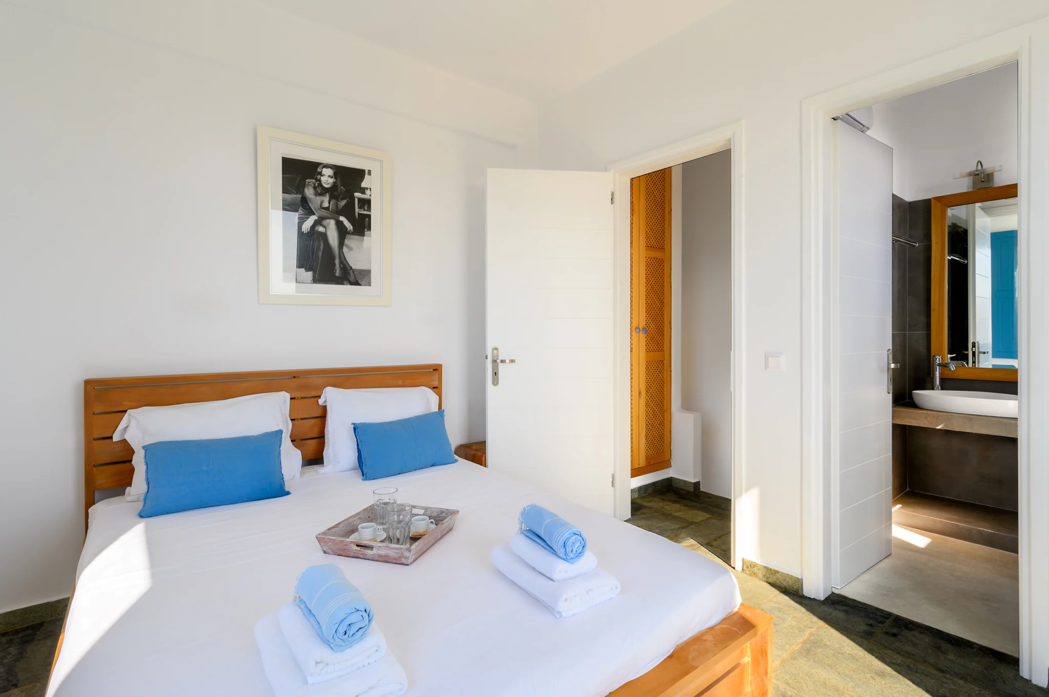 Villa Golden Beach — Bedroom and adjoining bathroom, Andros Bedroom with blue cushions, white walls and a view into the adjoining bathroom at Villa Golden Beach in Andros