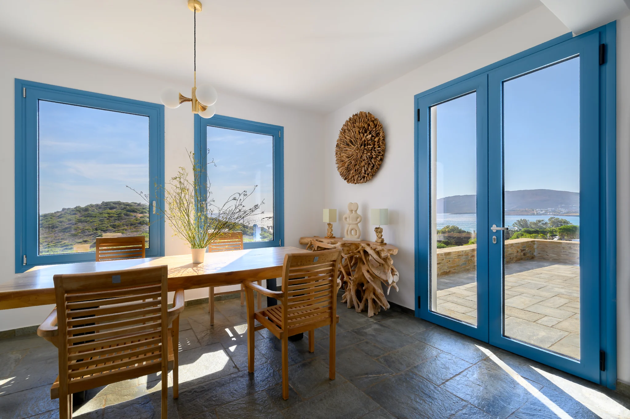 Villa Golden Beach — Dining room and blue doors, Andros Bright dining room with a timber table and blue glazed doors opening towards the terrace at Villa Golden Beach in Andros