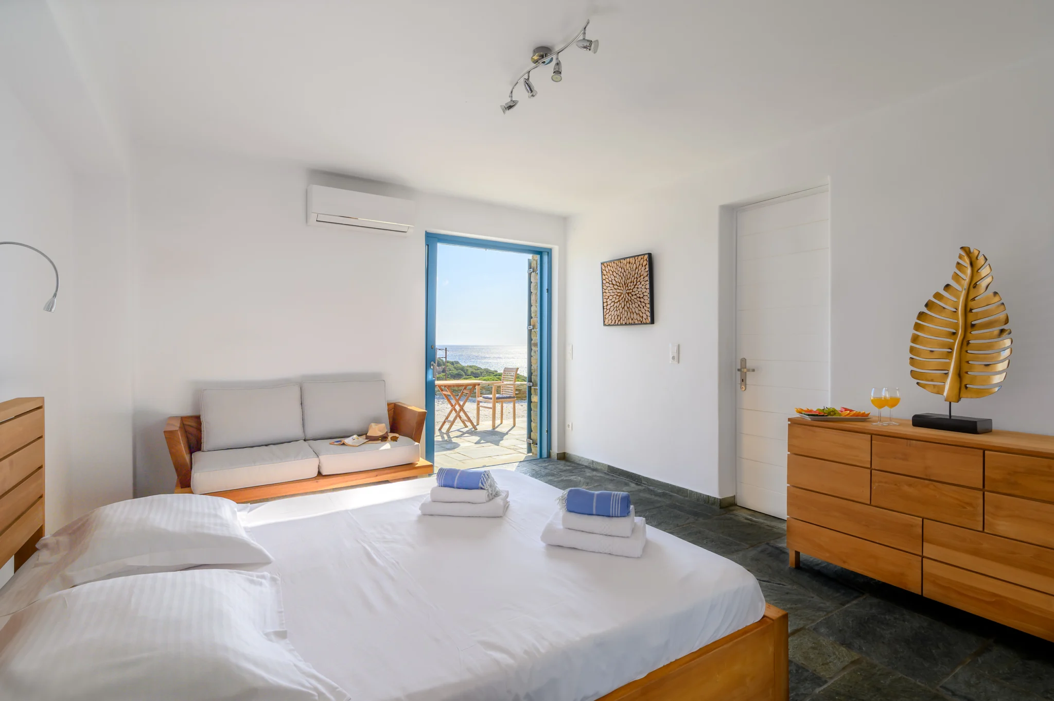 Villa Golden Beach — Bedroom and terrace doorway, Andros Bedroom with white linen, timber furniture and a blue doorway to the terrace at Villa Golden Beach in Andros