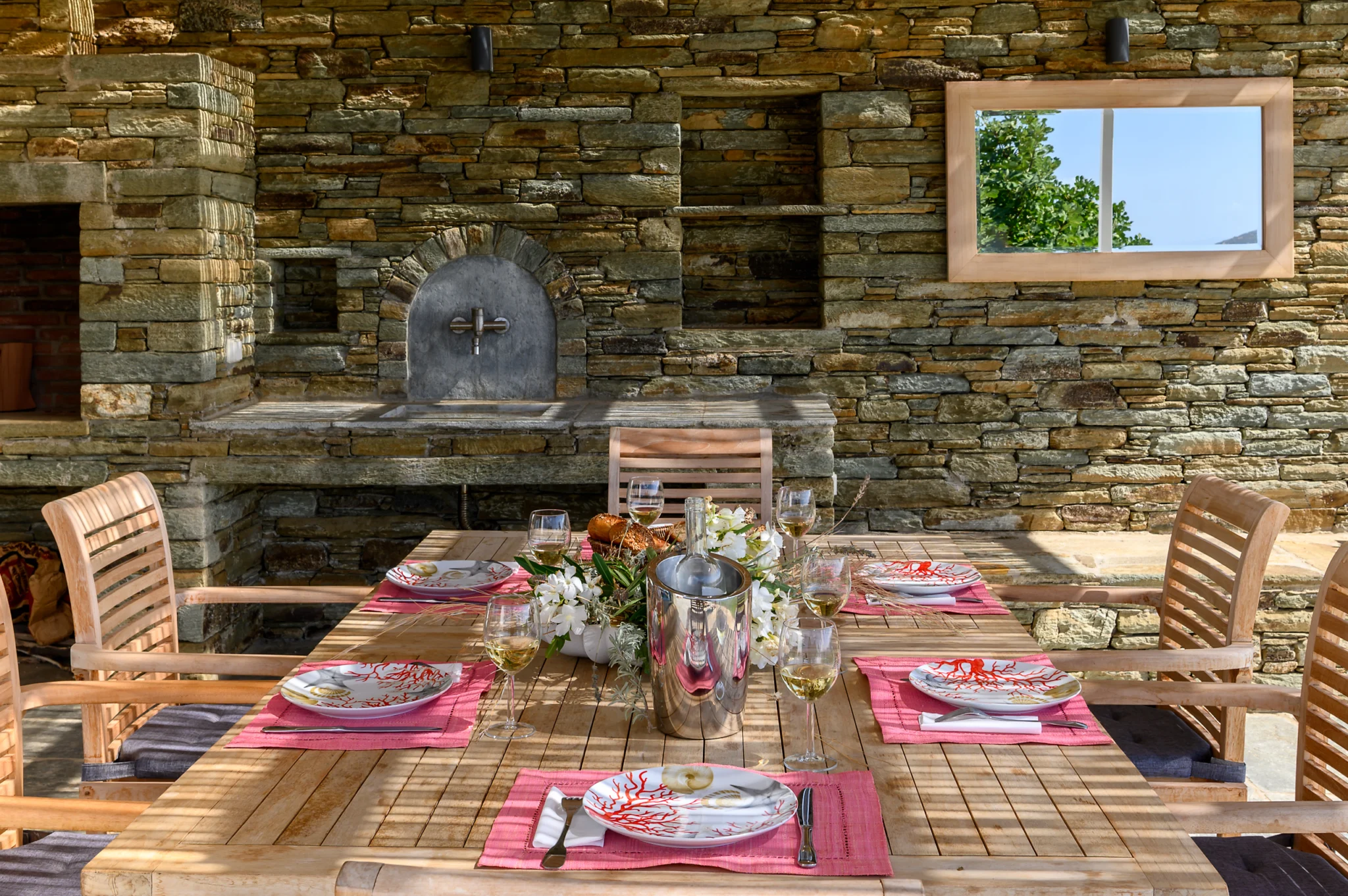 Villa Golden Beach — Outdoor dining, Andros Set timber dining table beneath a pergola against a stone wall at Villa Golden Beach in Andros