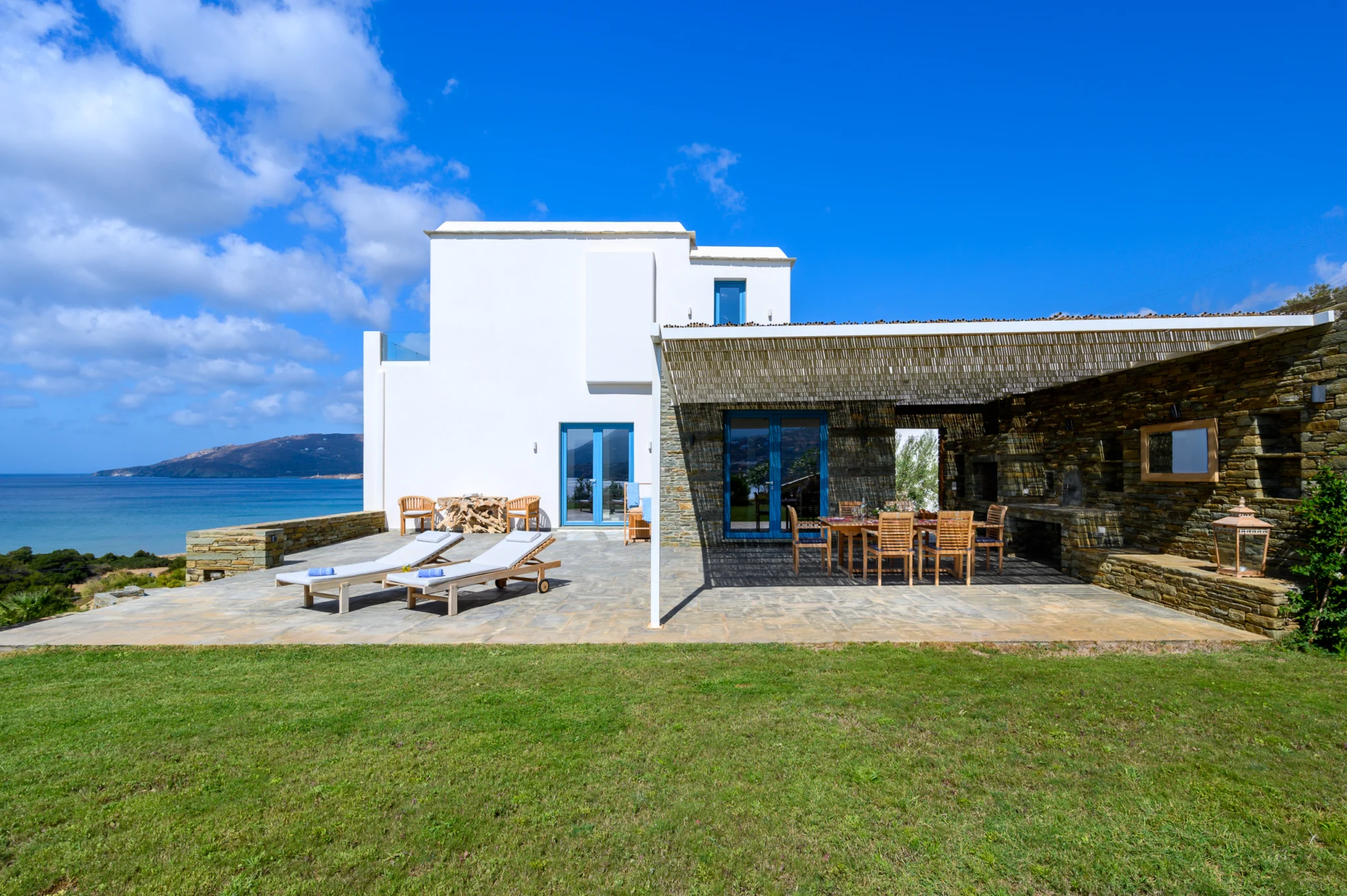 Villa Golden Beach — Garden and villa exterior, Andros Lawn beside the white villa and covered stone terrace with a sea view at Villa Golden Beach in Andros