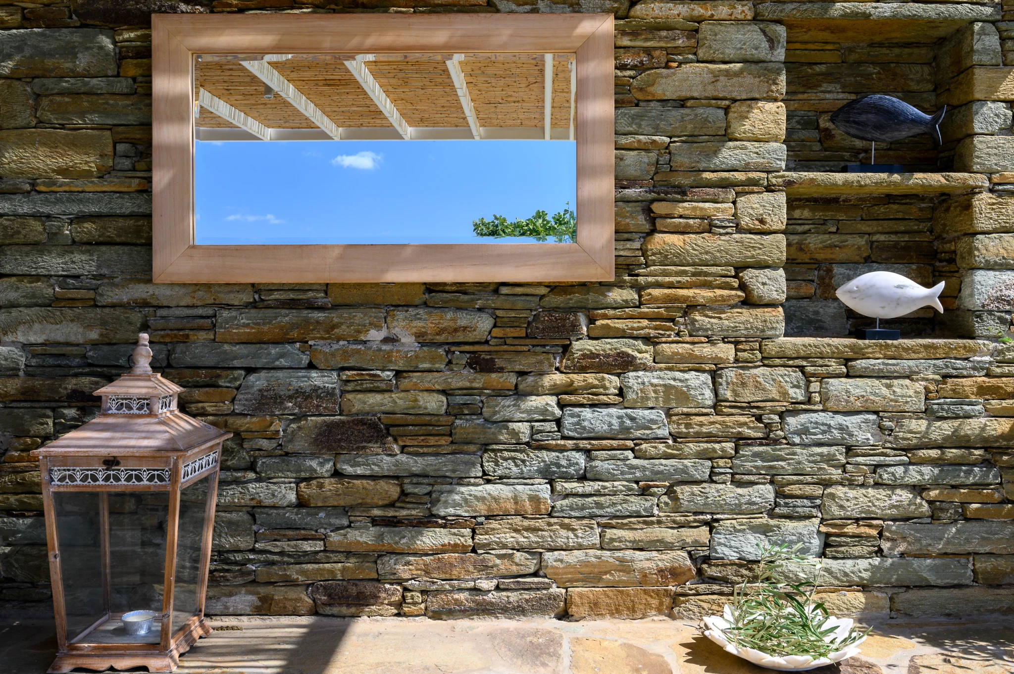 Villa Golden Beach — Stone wall and mirror detail, Andros Mirror, decorative fish and lantern on a stone terrace wall at Villa Golden Beach in Andros