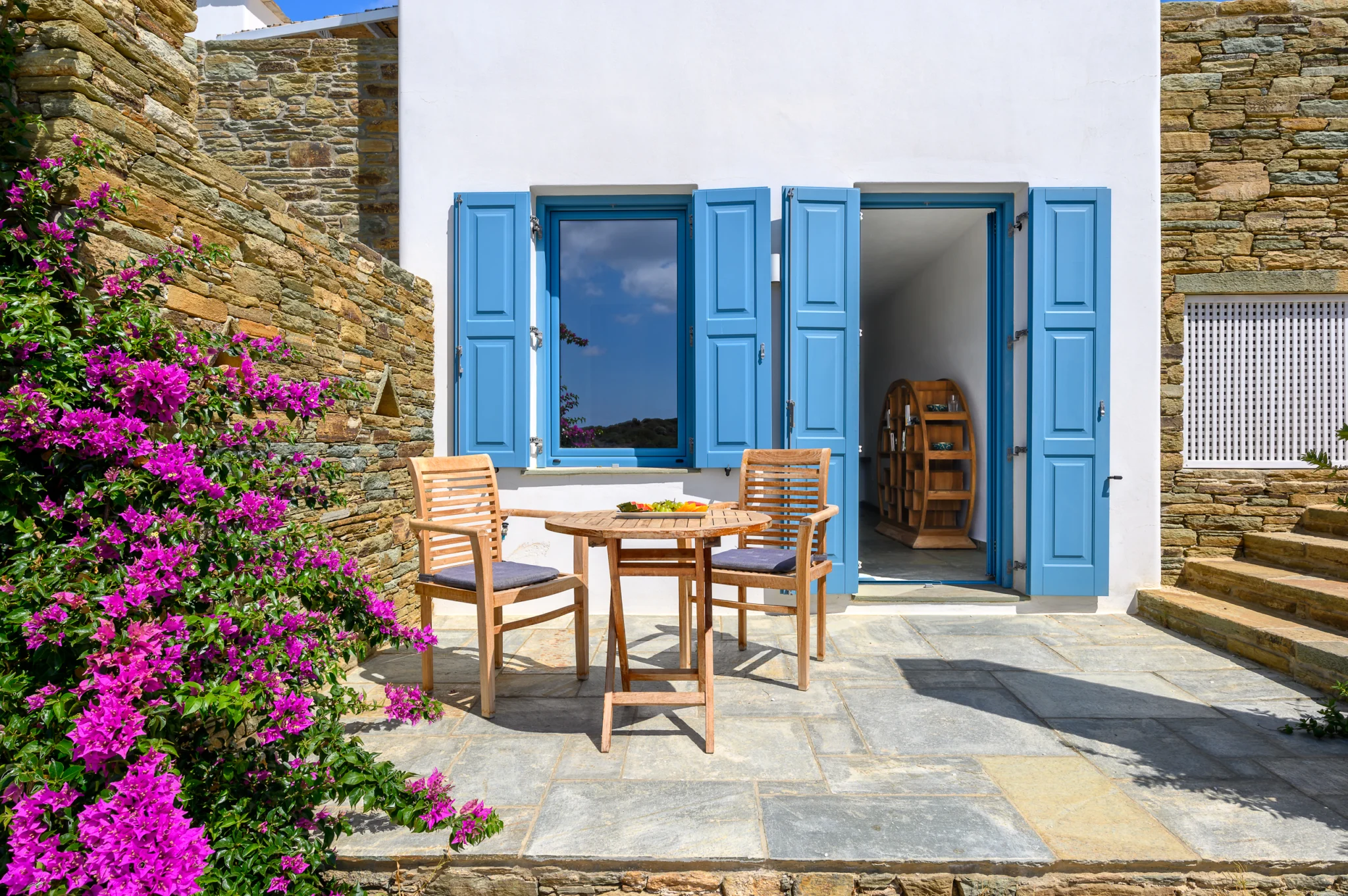 Villa Golden Beach — Courtyard and bougainvillea, Andros Courtyard table beside blue shutters and flowering bougainvillea at Villa Golden Beach in Andros