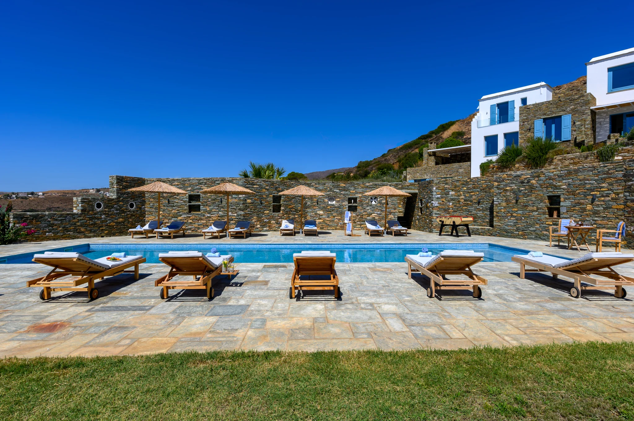 Villa Golden Beach — Pool terrace and sun loungers, Andros Sun loungers around the swimming pool below stone terraces at Villa Golden Beach in Andros