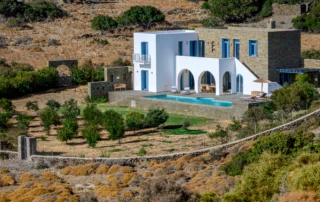 Villa Thalassa with white arches, stone walls and a pool above an olive grove in Andros, Greece