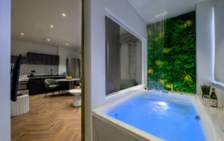 Indoor jacuzzi with blue lighting, overhead shower and foliage wall at Alpha Luxury Apartments in Athens