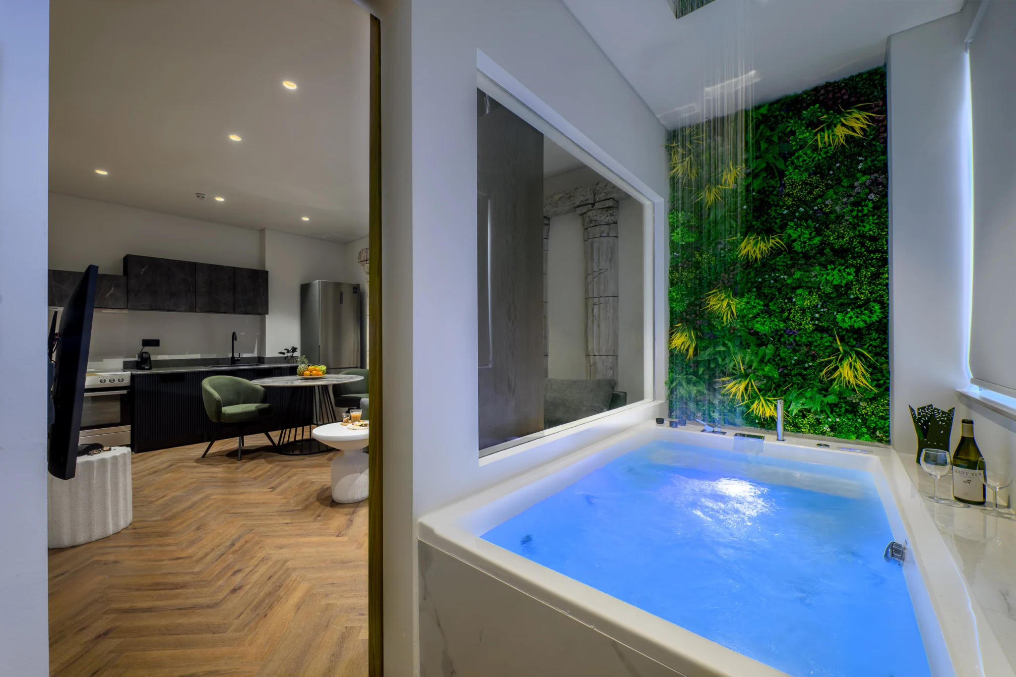 Indoor jacuzzi with blue lighting, overhead shower and foliage wall at Alpha Luxury Apartments in Athens
