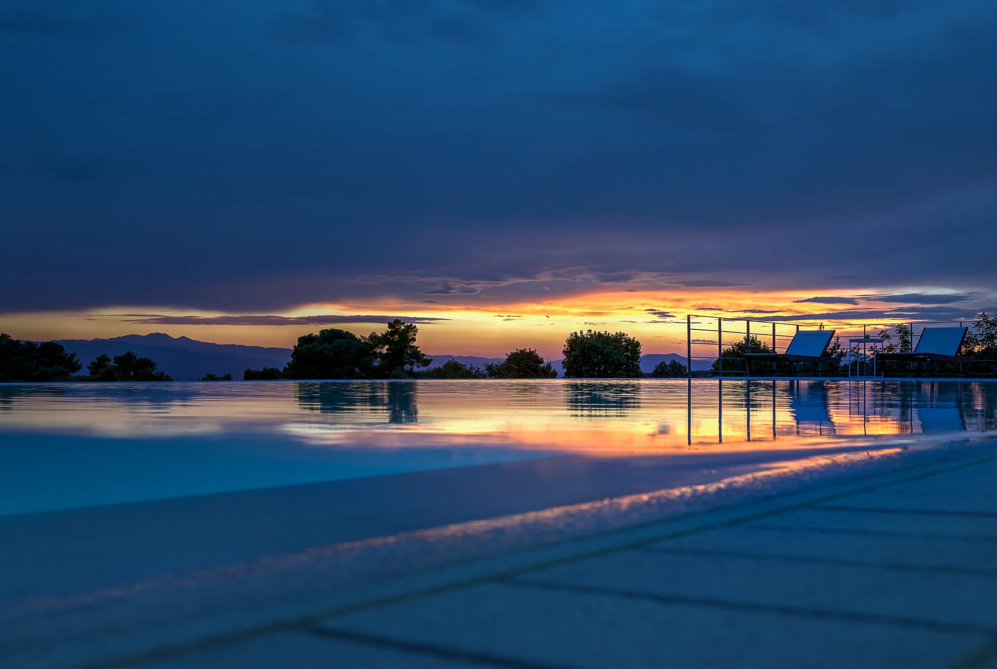 Villa terrace and infinity pool overlooking the sea at sunset