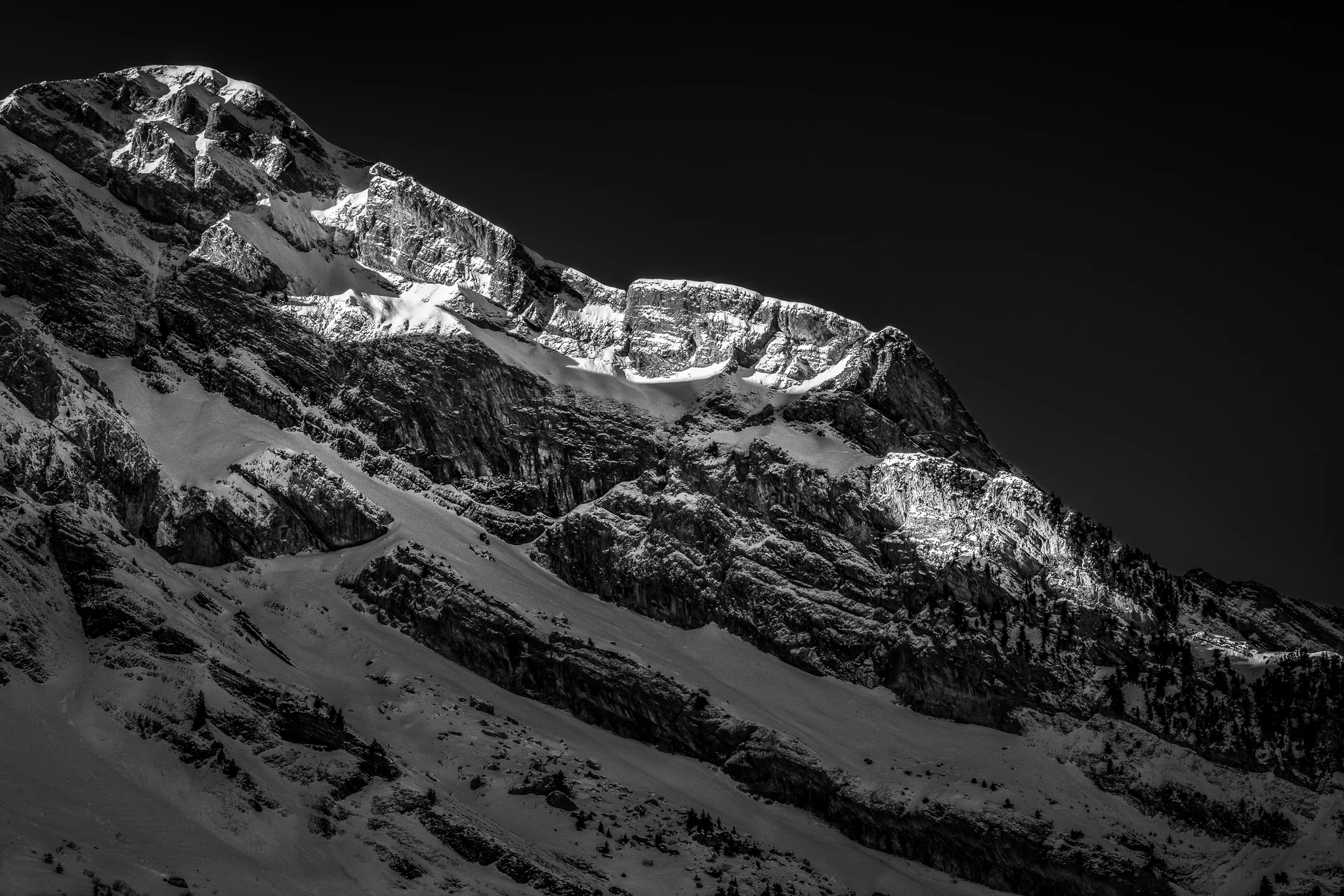 Black-and-white view of a rugged snow-covered mountain face