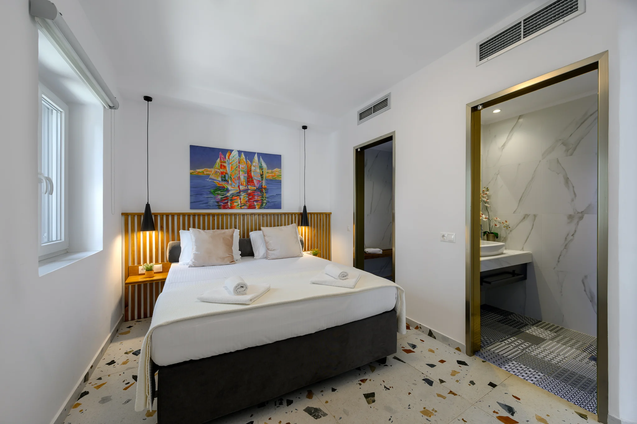 Bedroom with an adjoining bathroom and patterned floor tiles at Blue Sky House, Pylos, Peloponnese, Greece.
