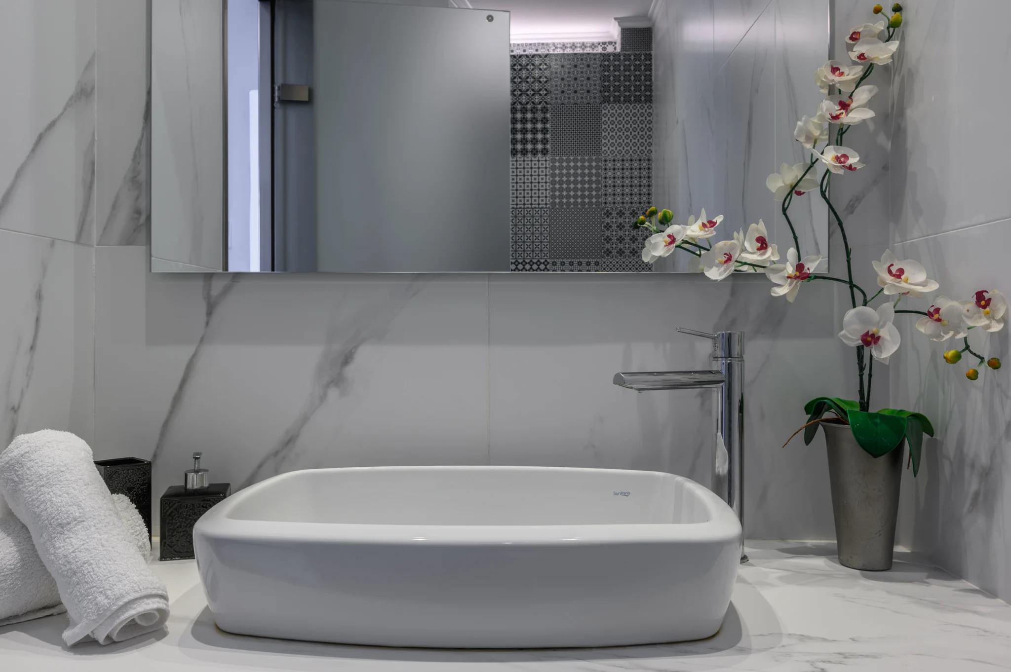 Bathroom basin with a mirrored cabinet and marble-effect wall at Blue Sky House, Pylos, Peloponnese, Greece.