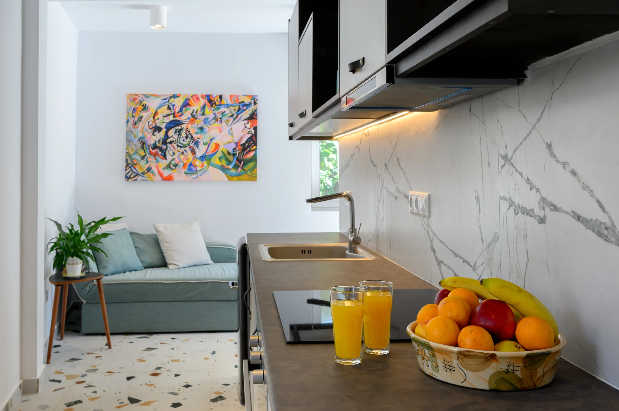 Kitchen counter with fruit and orange juice beside a seating area at Blue Sky House, Pylos, Peloponnese, Greece.