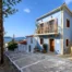 Blue house and paved forecourt framed by an olive tree at Blue Sky House, Pylos, Peloponnese, Greece.