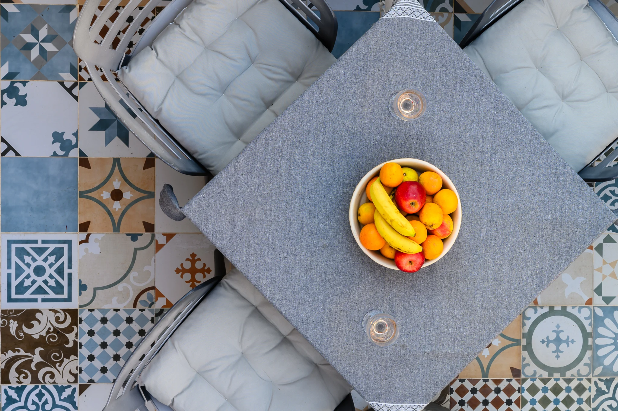 Overhead view of a dining table, fruit bowl and patterned floor tiles at Blue Sky House, Pylos, Peloponnese, Greece.