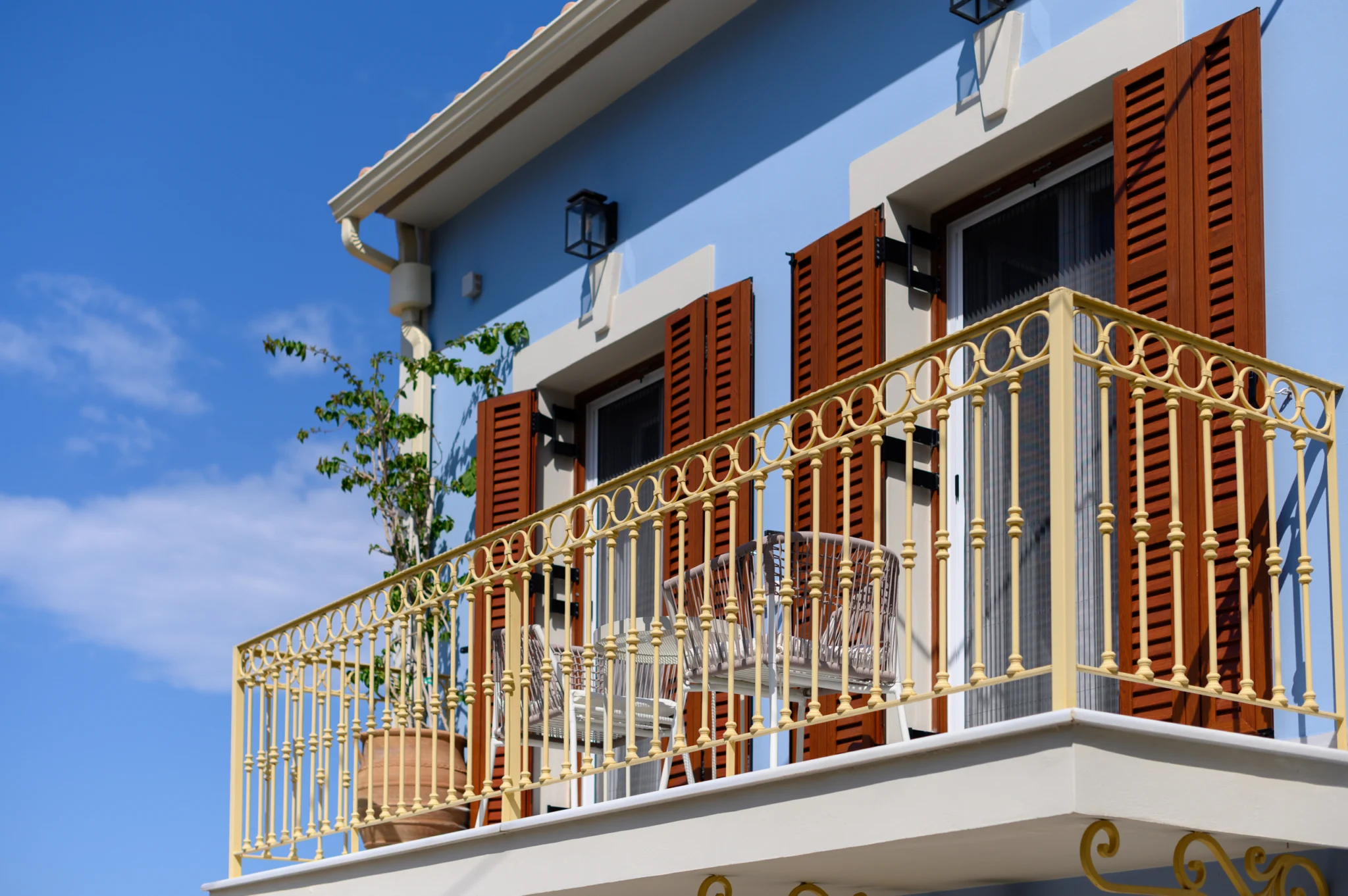 Decorative balcony railing and timber shutters on the blue facade at Blue Sky House, Pylos, Peloponnese, Greece.