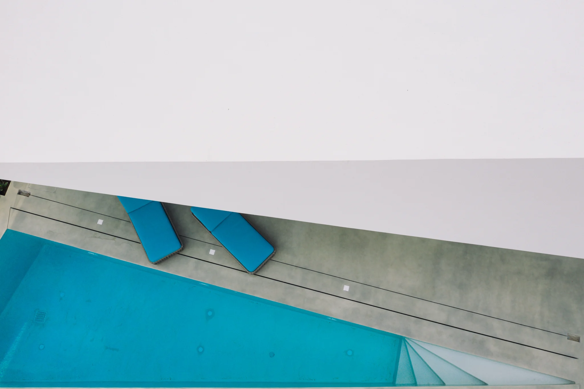 White roof geometry above a turquoise pool and terrace at Contemporary Minimalistic Villa, Athens, Attica, Greece.