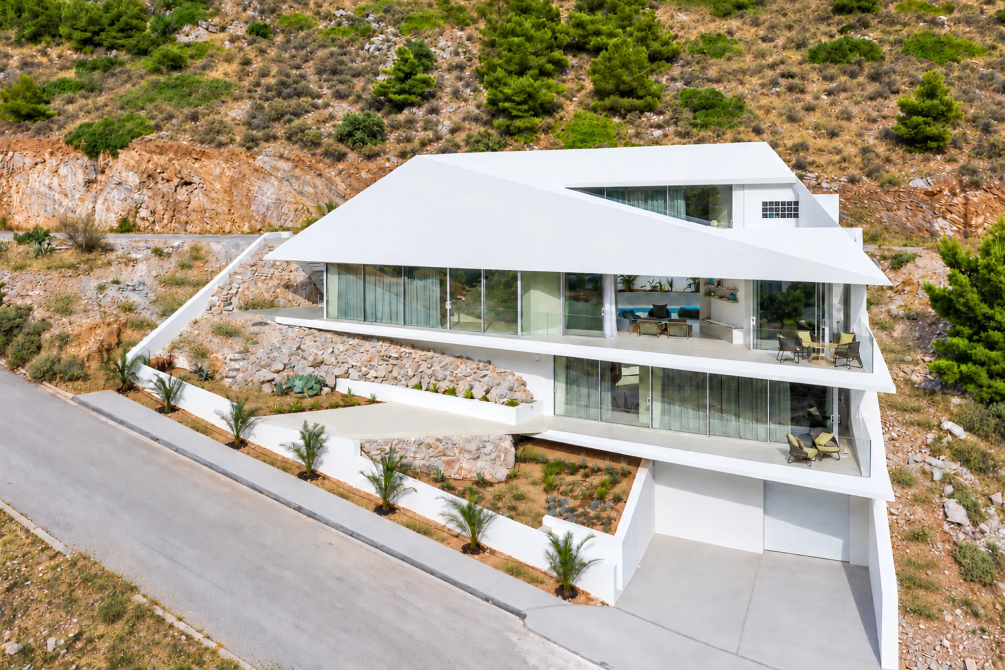 Aerial view of the villa, terraces and hillside setting at Contemporary Minimalistic Villa, Athens, Attica, Greece.
