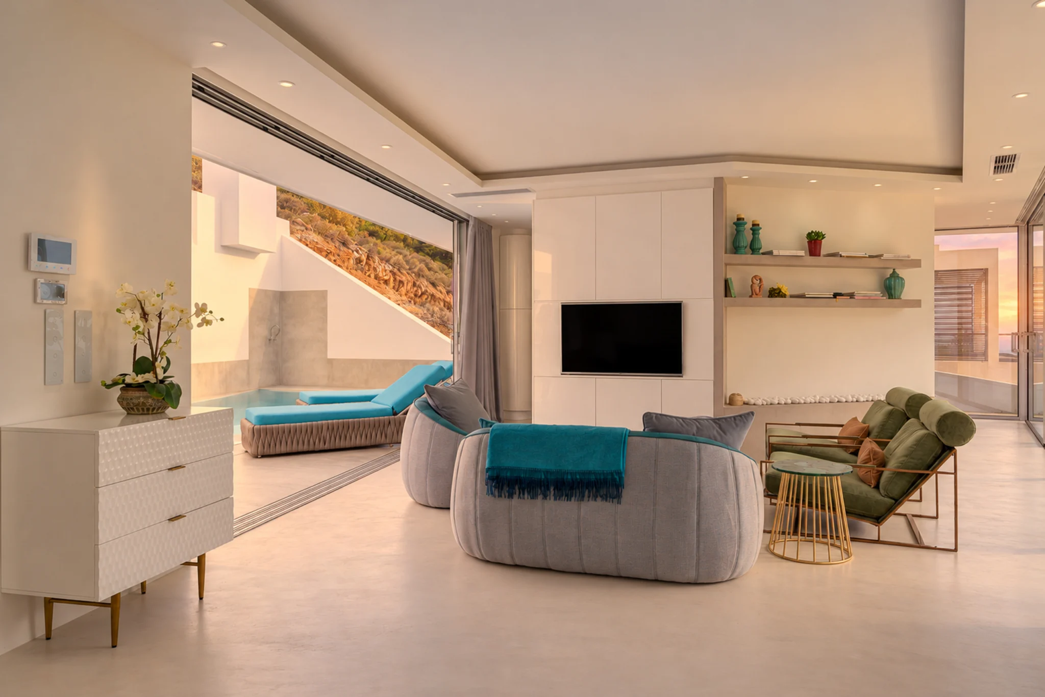 Living room with teal seating opening to the courtyard in evening light at Contemporary Minimalistic Villa, Athens, Attica, Greece.