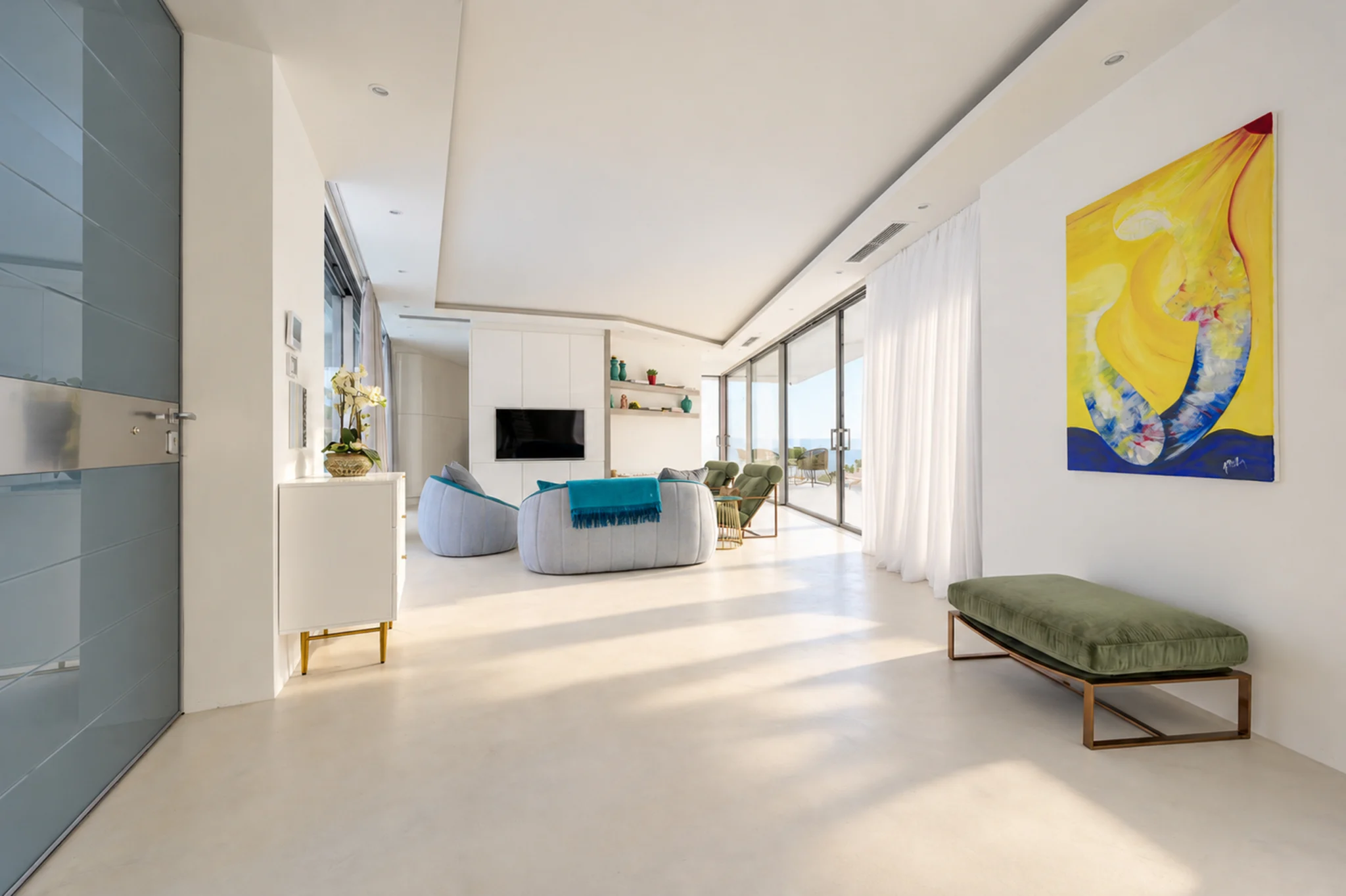 Long living area with glazed walls, teal seating and colourful artwork at Contemporary Minimalistic Villa, Athens, Attica, Greece.