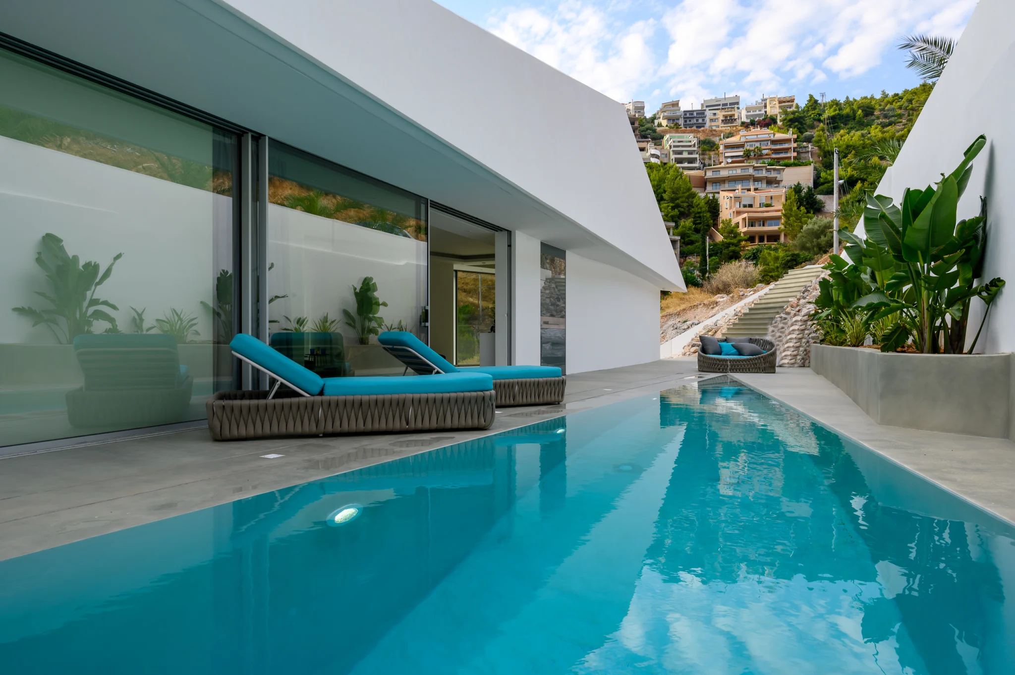 Courtyard pool beside the glazed living area in daylight at Contemporary Minimalistic Villa, Athens, Attica, Greece.