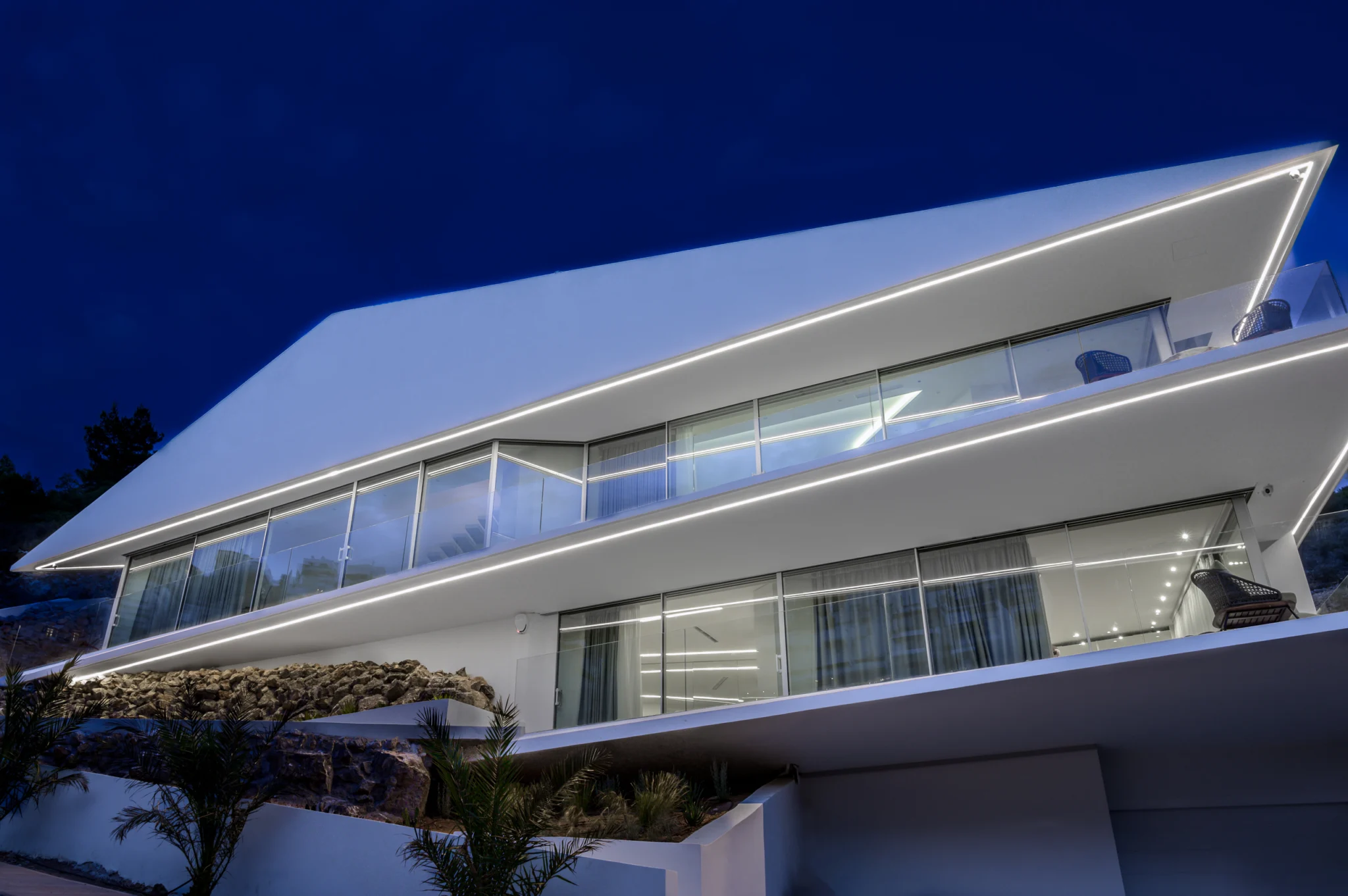 Illuminated facade and balconies beneath a deep blue sky at Contemporary Minimalistic Villa, Athens, Attica, Greece.