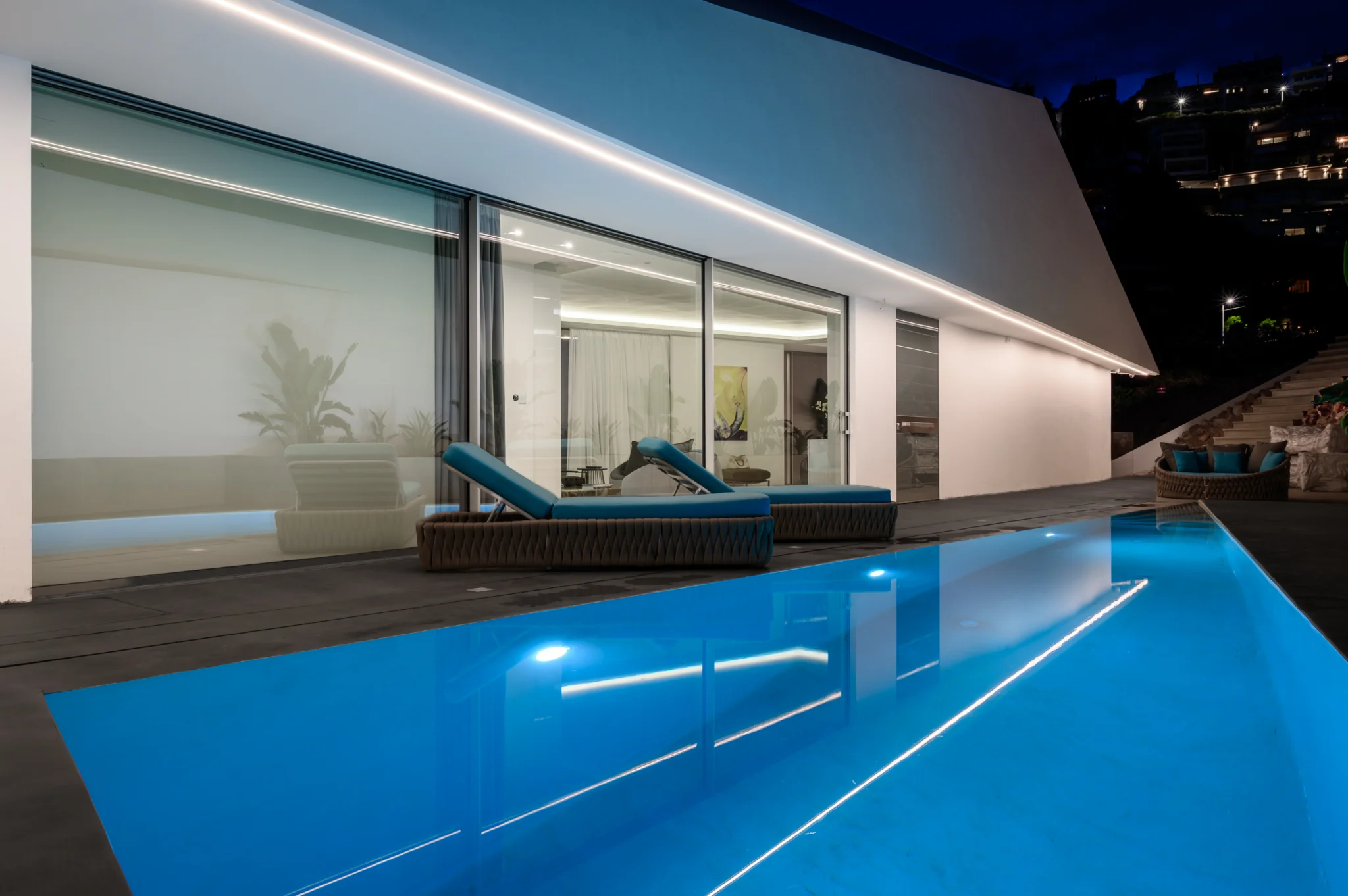Illuminated turquoise courtyard pool beside the living area at night at Contemporary Minimalistic Villa, Athens, Attica, Greece.