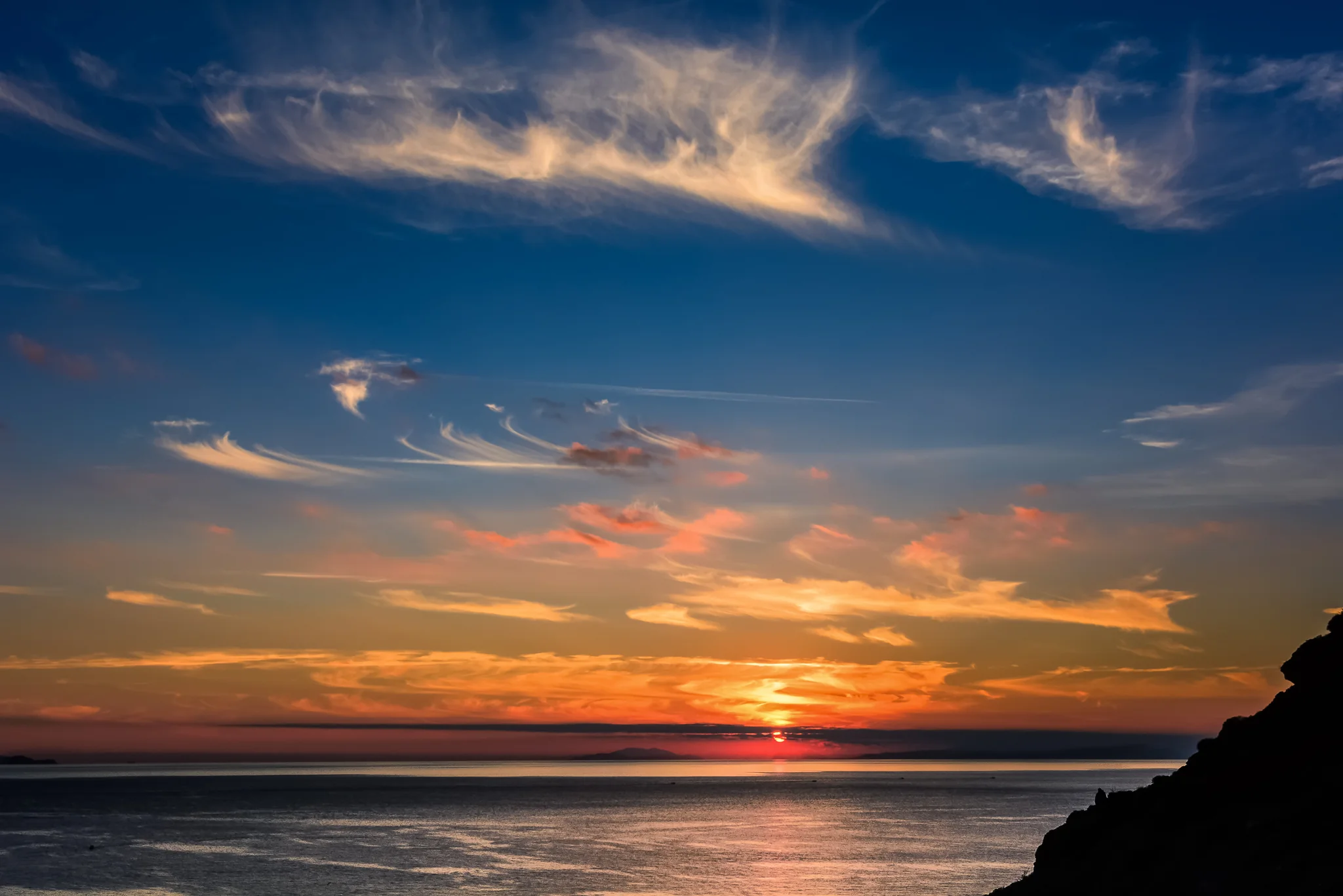 Dramatic orange and purple sunset spreading across the open sea
