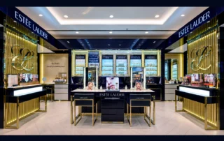 Frontal view of the Estée Lauder beauty counters with navy and gold displays at Hondos Center, Glyfada.