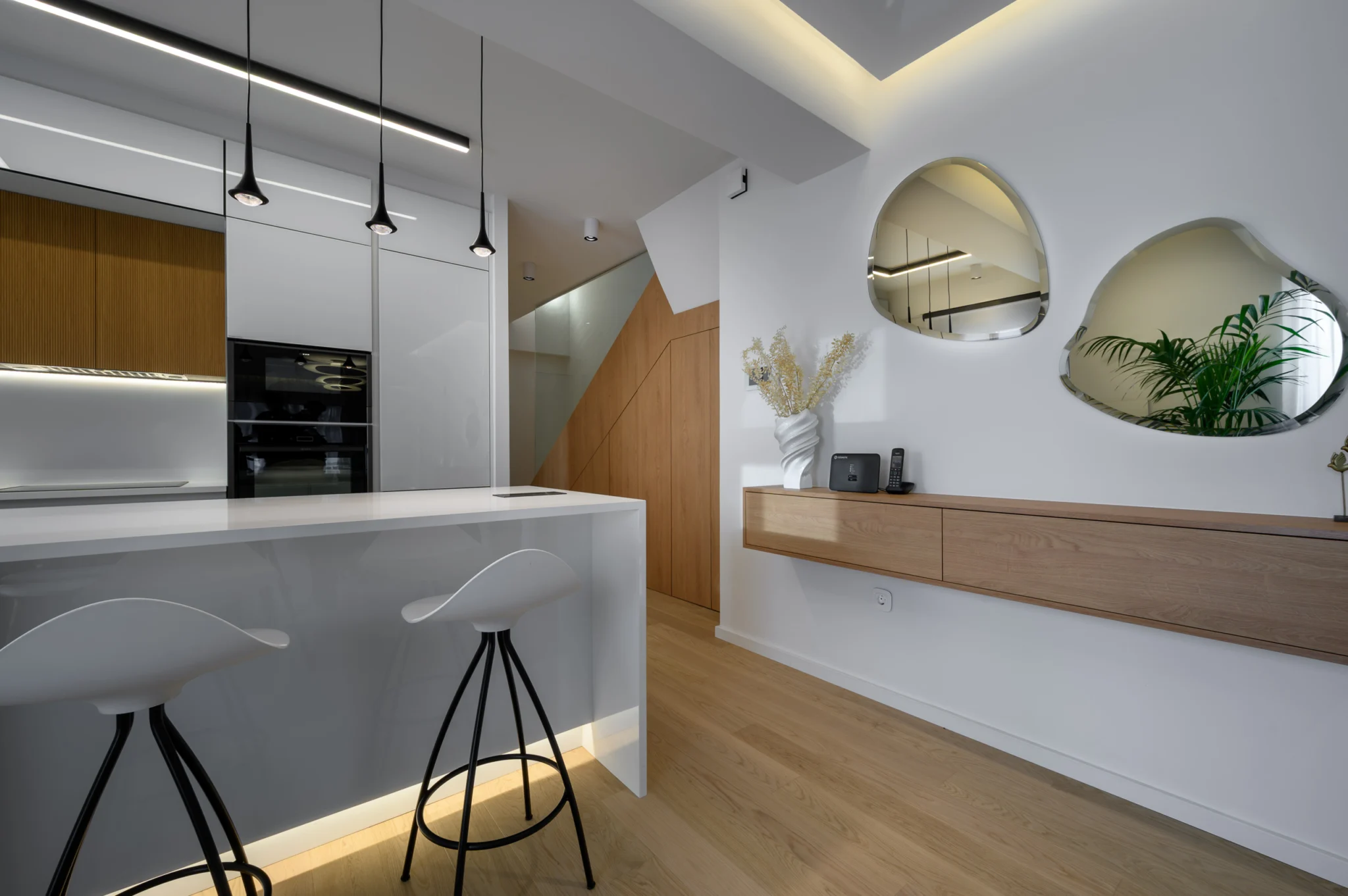 FOUNTIS apartment, Northern Athens — White kitchen island beside a floating timber console and organic mirrors White kitchen island beside a floating timber console and organic mirrors in a luxury apartment in northern Athens.