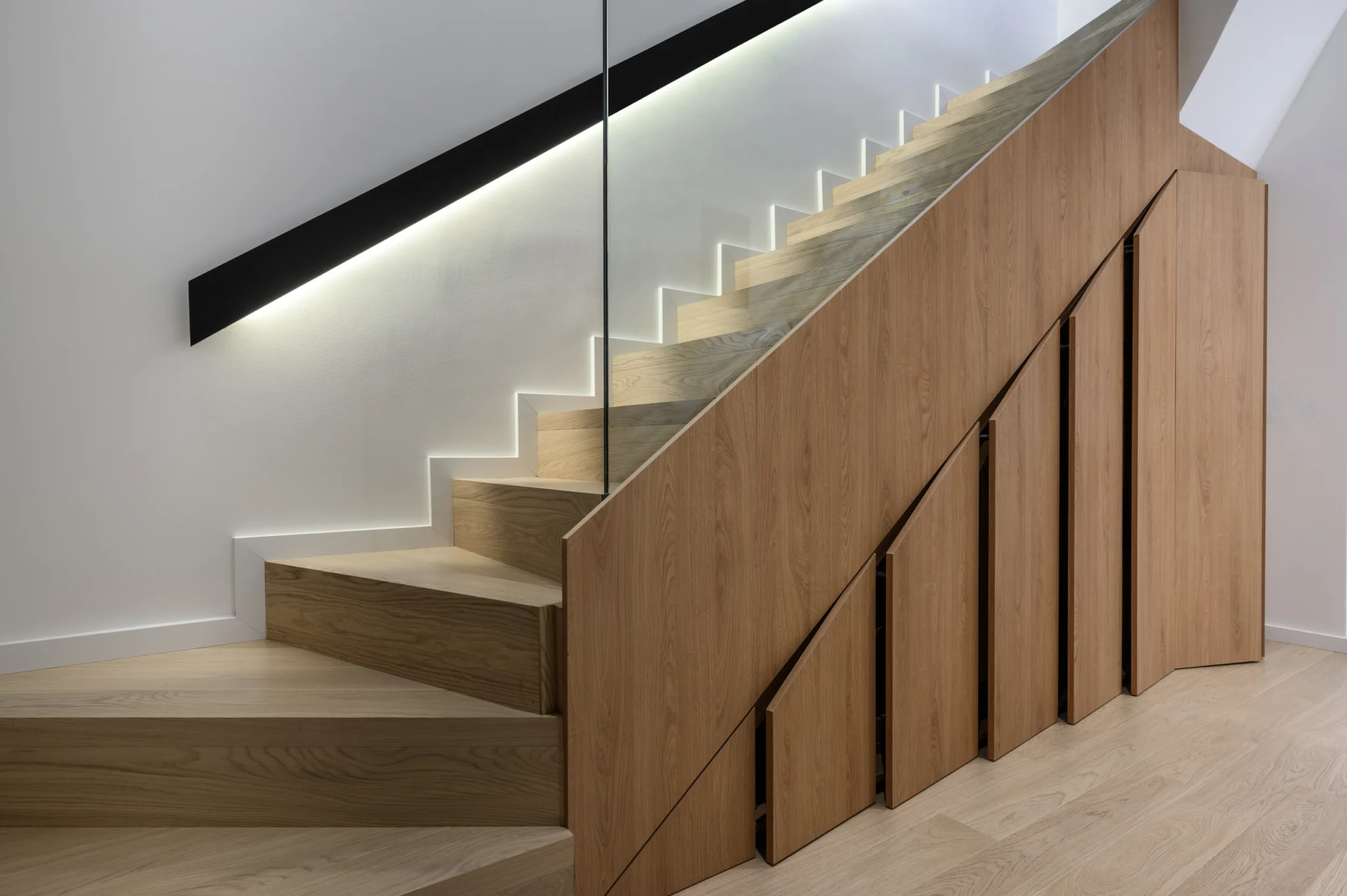 FOUNTIS apartment, Northern Athens — Timber staircase with glass balustrade, illuminated handrail and storage below Timber staircase with glass balustrade, illuminated handrail and storage below in a luxury apartment in northern Athens.