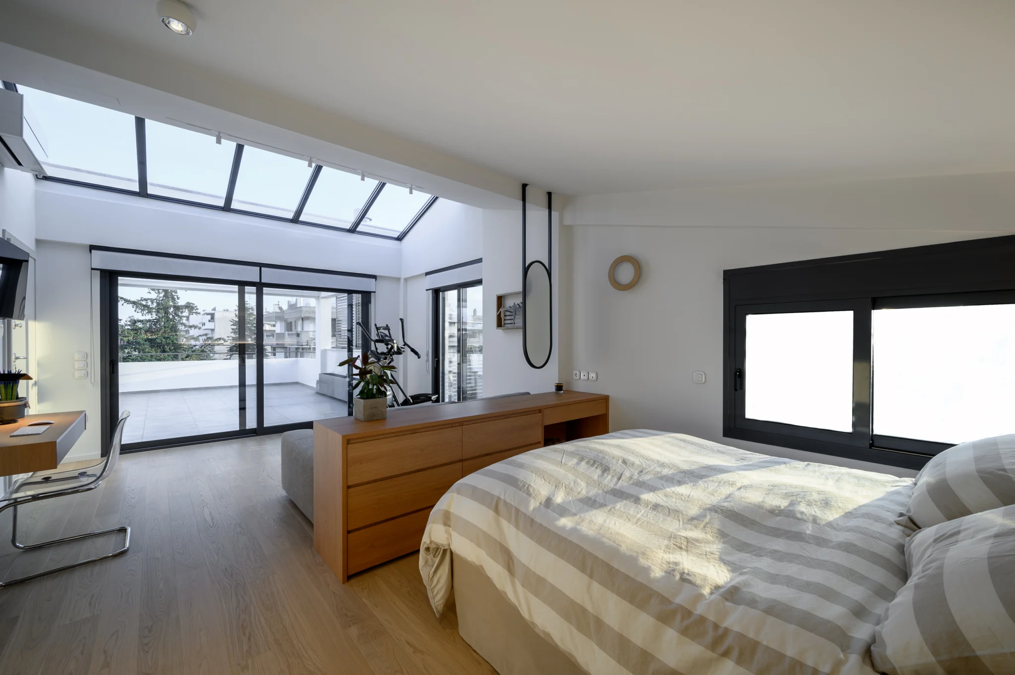 FOUNTIS apartment, Northern Athens — Upper-level bedroom with timber divider, roof glazing and terrace doors Upper-level bedroom with timber divider, roof glazing and terrace doors in a luxury apartment in northern Athens.
