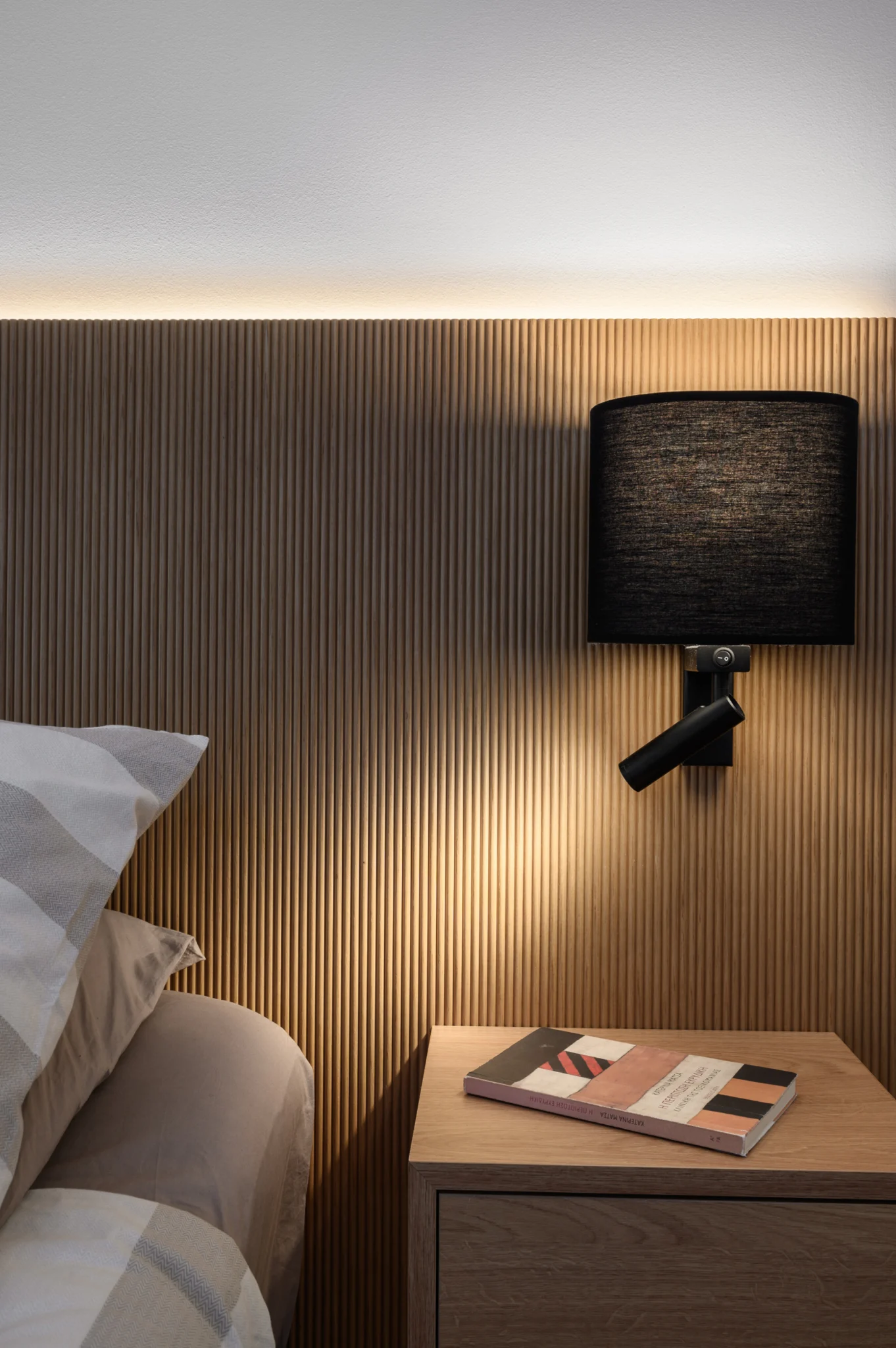 FOUNTIS apartment, Northern Athens — Black bedside reading lamp against a ribbed timber headboard Black bedside reading lamp against a ribbed timber headboard in a luxury apartment in northern Athens.