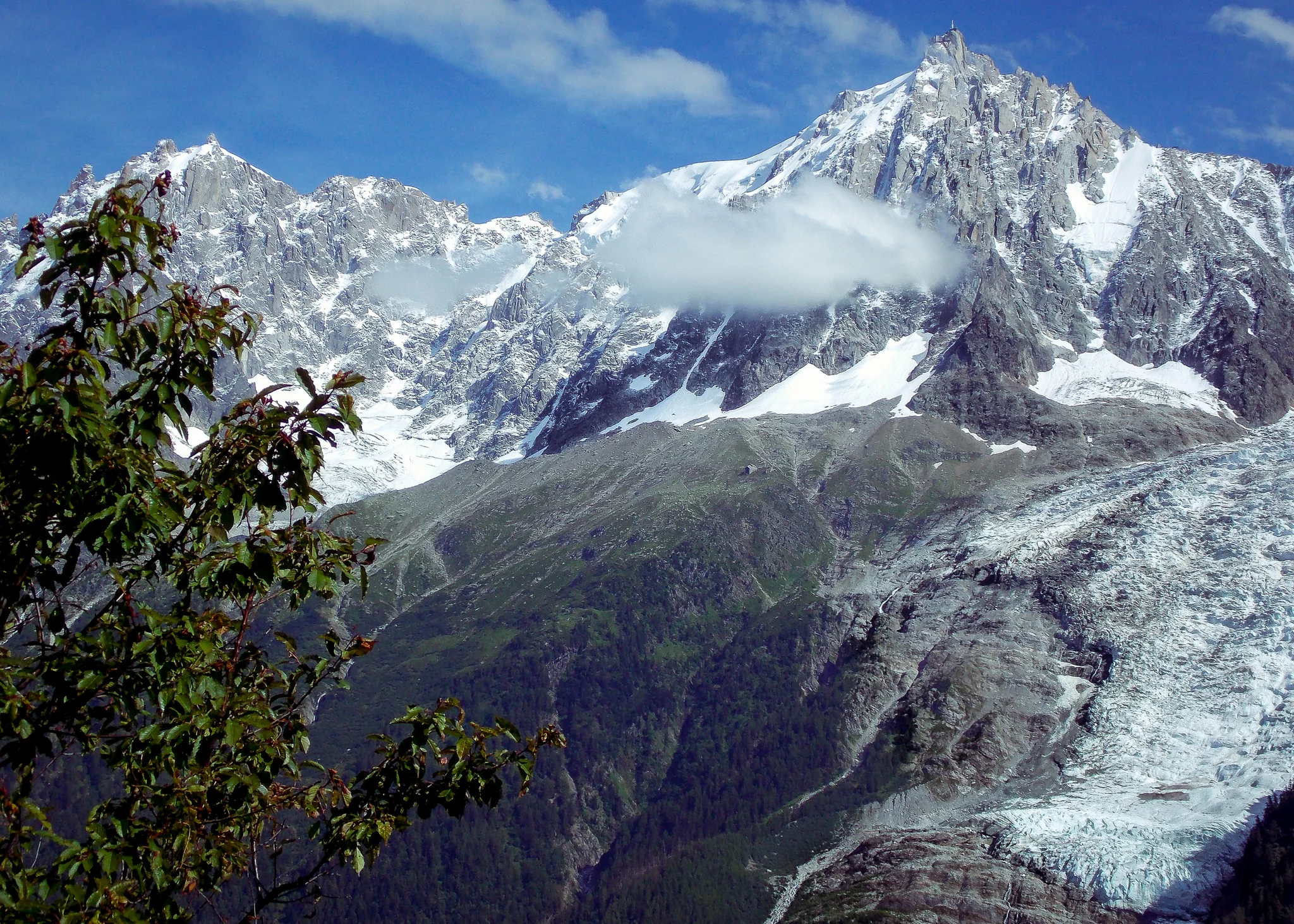 Glaciated alpine mountain peak emerging through low cloud