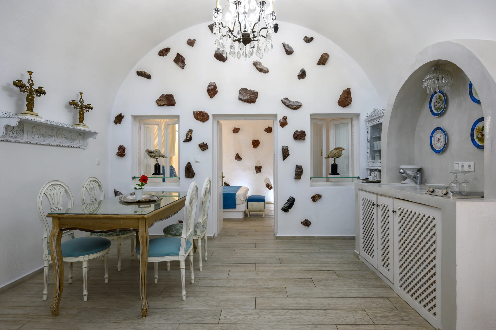 Intermezzo, Santorini — Dining area and kitchenette beneath a vaulted ceiling with a view into the bedroom Dining area and kitchenette beneath a vaulted ceiling with a view into the bedroom at Intermezzo in Santorini.
