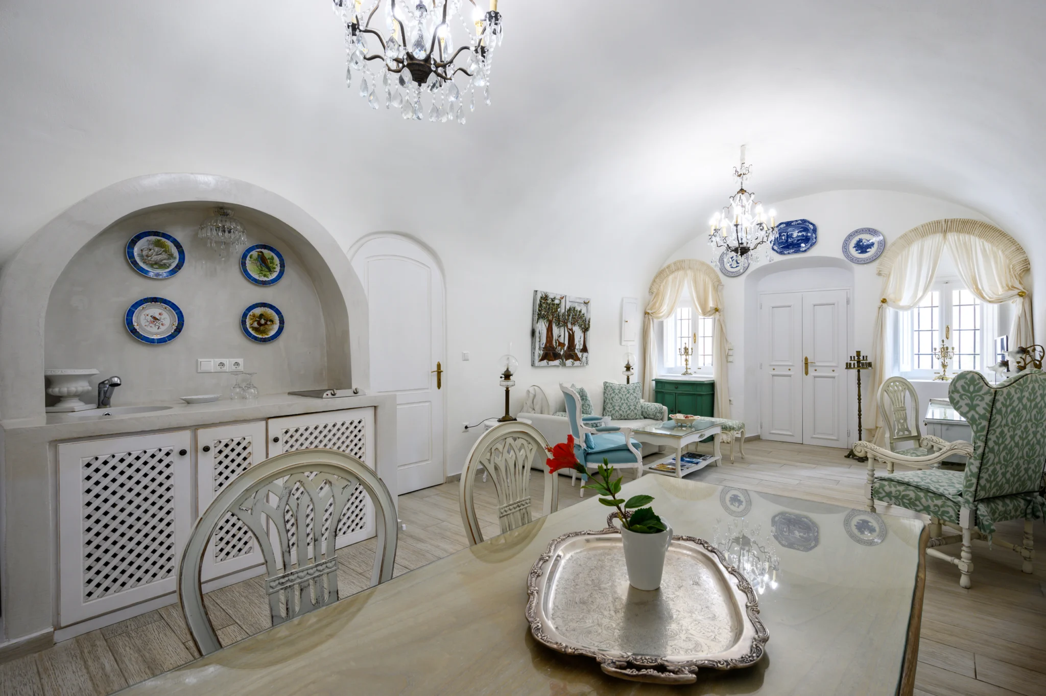 Intermezzo, Santorini — Living and dining spaces with chandeliers, white cabinetry and pale green upholstery Living and dining spaces with chandeliers, white cabinetry and pale green upholstery at Intermezzo in Santorini.