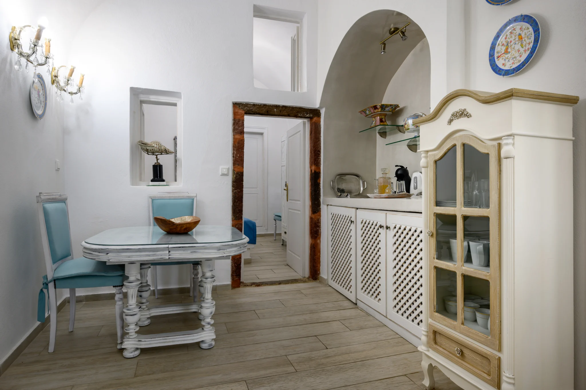 Intermezzo, Santorini — Dining nook with pale blue chairs, lattice-front cabinetry and an arched kitchenette Dining nook with pale blue chairs, lattice-front cabinetry and an arched kitchenette at Intermezzo in Santorini.