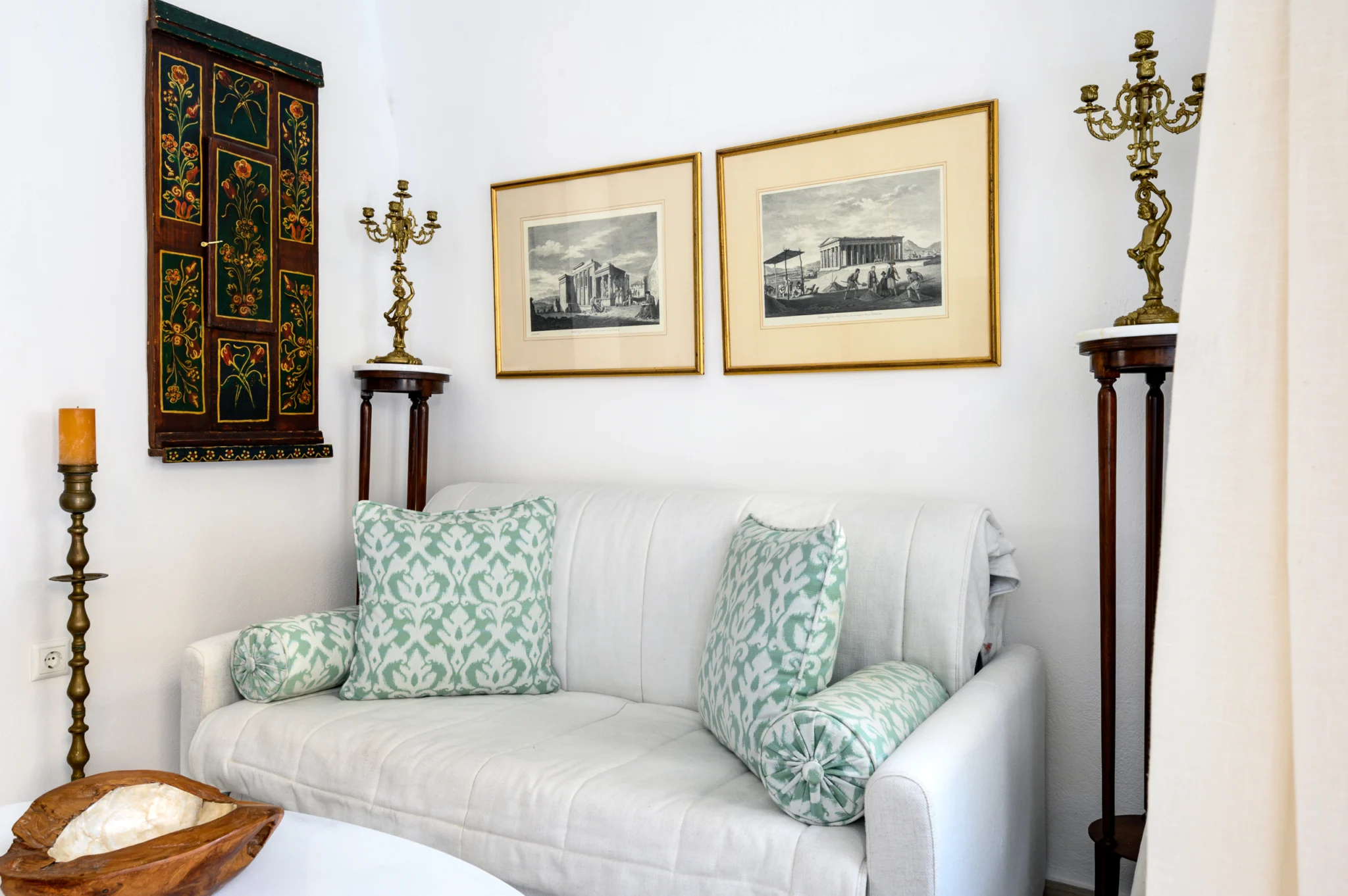 Intermezzo, Santorini — Sofa detail with green patterned cushions, framed prints and decorative candlesticks Sofa detail with green patterned cushions, framed prints and decorative candlesticks at Intermezzo in Santorini.