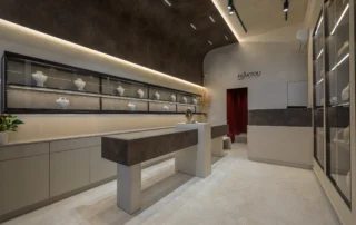 Jewelry shop interior in Korydallos, Athens, with a long illuminated wall display, freestanding counters and a curved dark ceiling.
