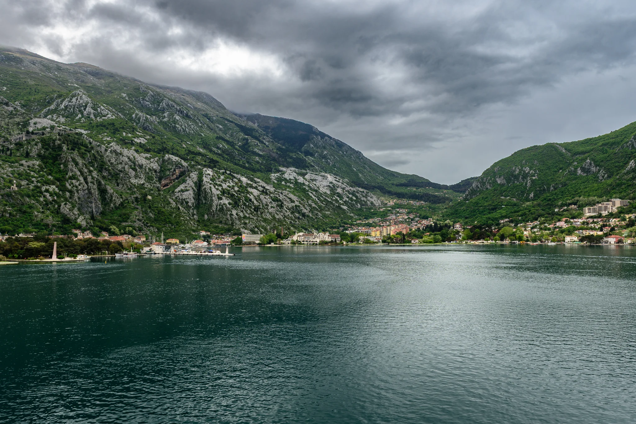 Waterfront town on Kotor Bay beneath steep green mountains in Montenegro