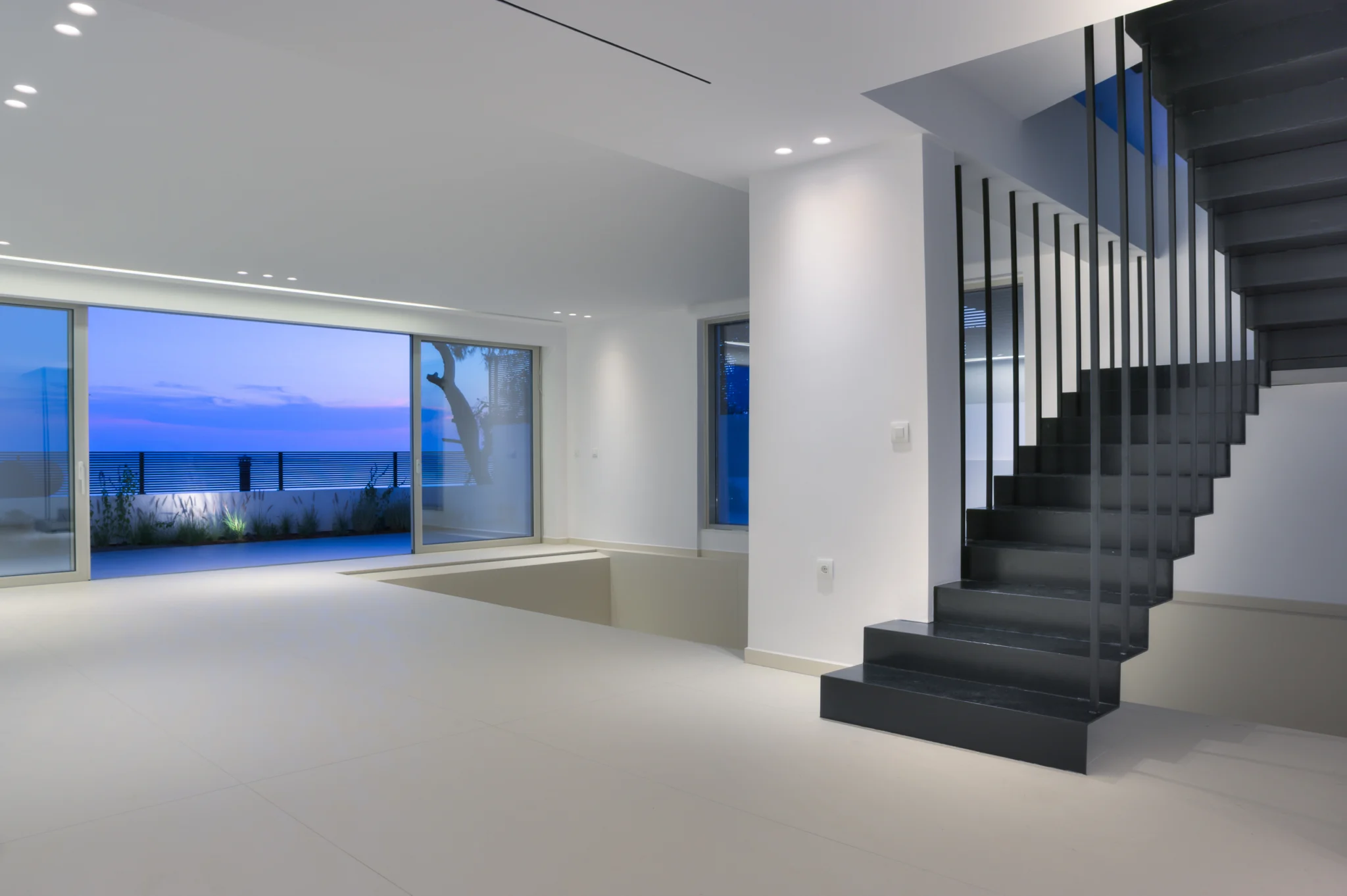Black staircase in an illuminated white interior at twilight at Luxury Residence Blackstone.