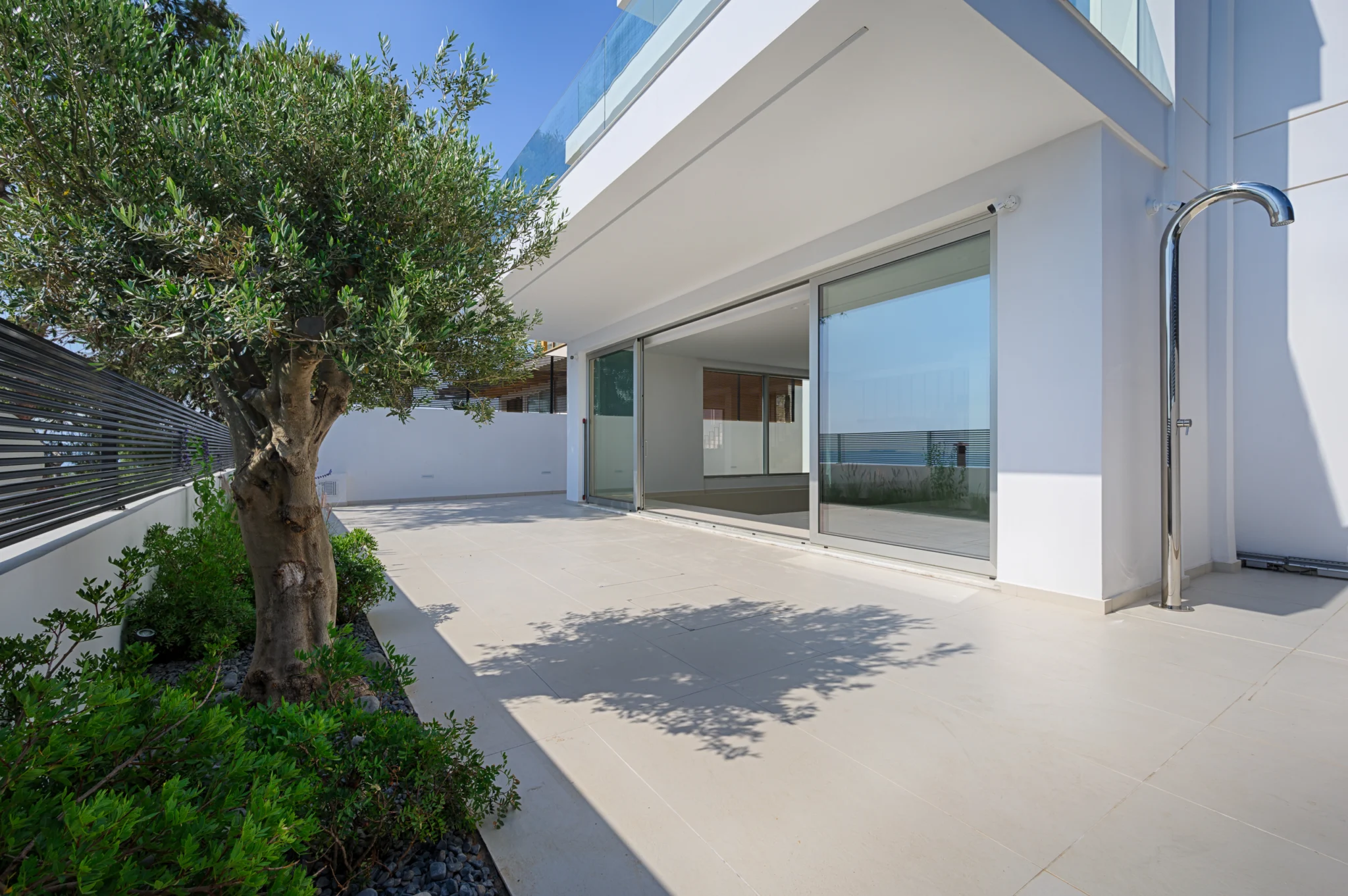 White terrace with an olive tree, sliding glazing and an outdoor shower at Luxury Residence Blackstone.