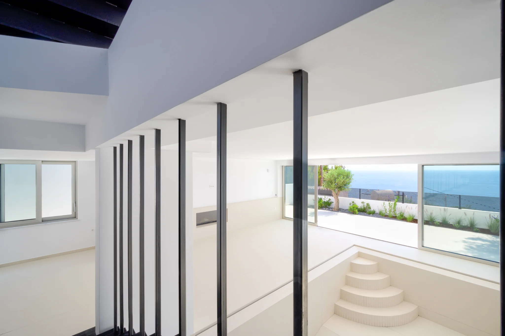Black stair balusters above curved white steps beside sea-facing glazing at Luxury Residence Blackstone.
