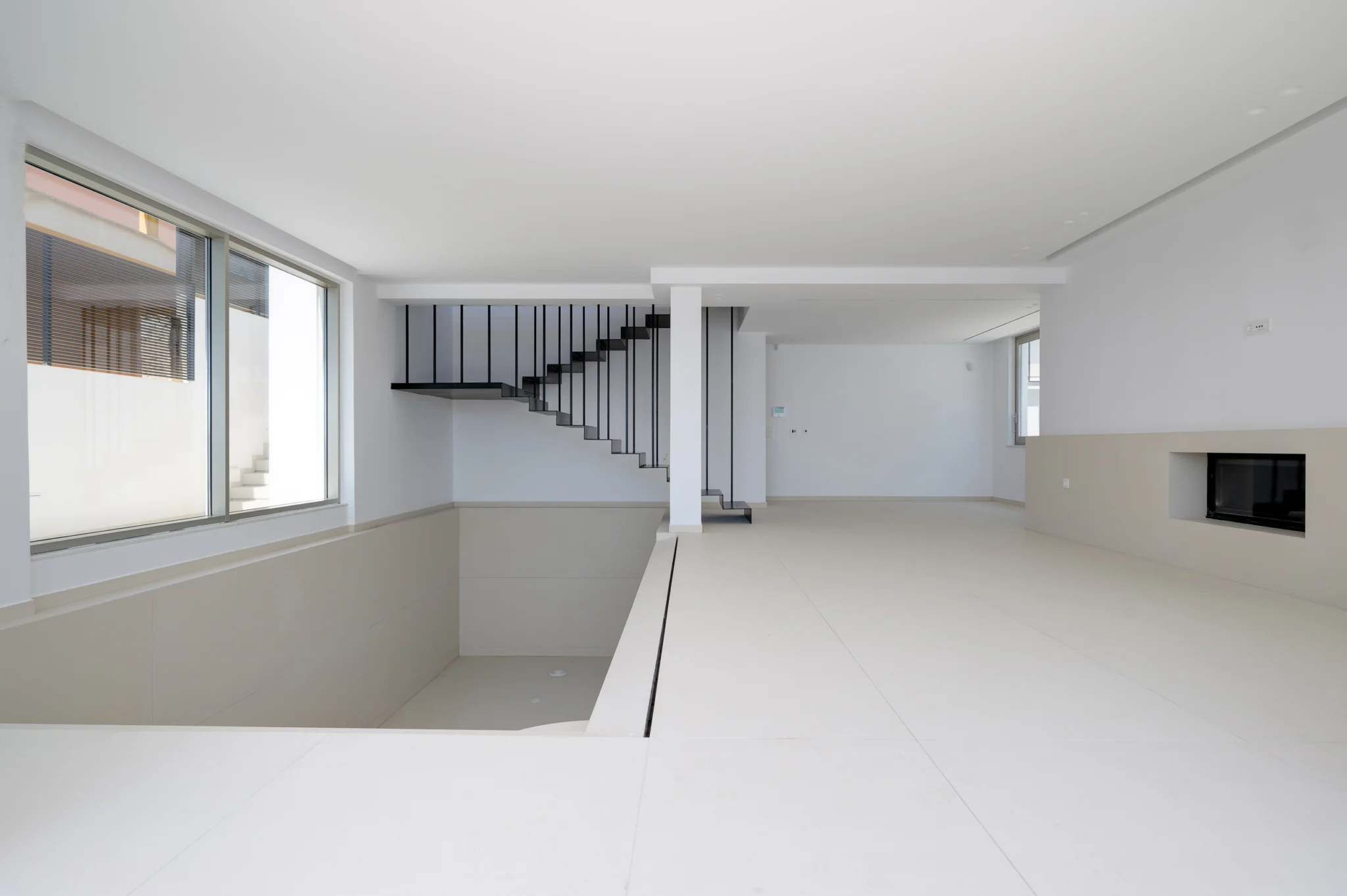 Open white interior with a recessed fireplace and staircase at Luxury Residence Blackstone.