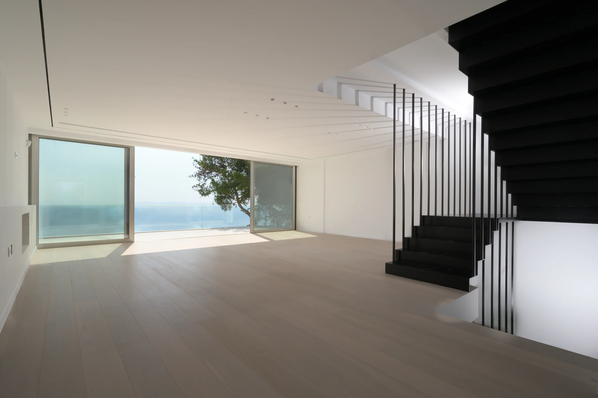 Sea-facing unfurnished interior with a black staircase and pale flooring at Luxury Residence Blackstone.