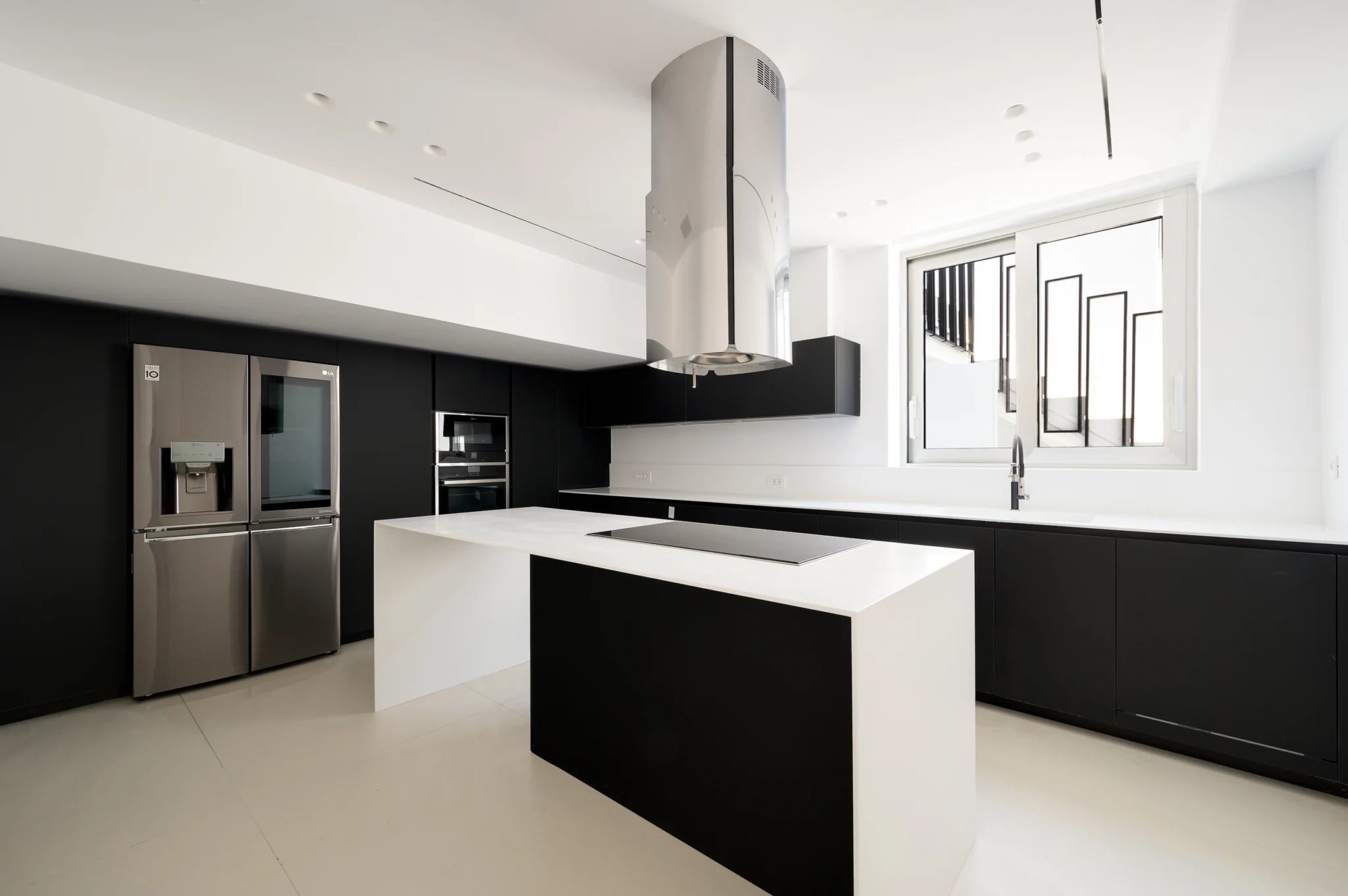 Black-and-white kitchen with an island and cylindrical extractor at Luxury Residence Blackstone.