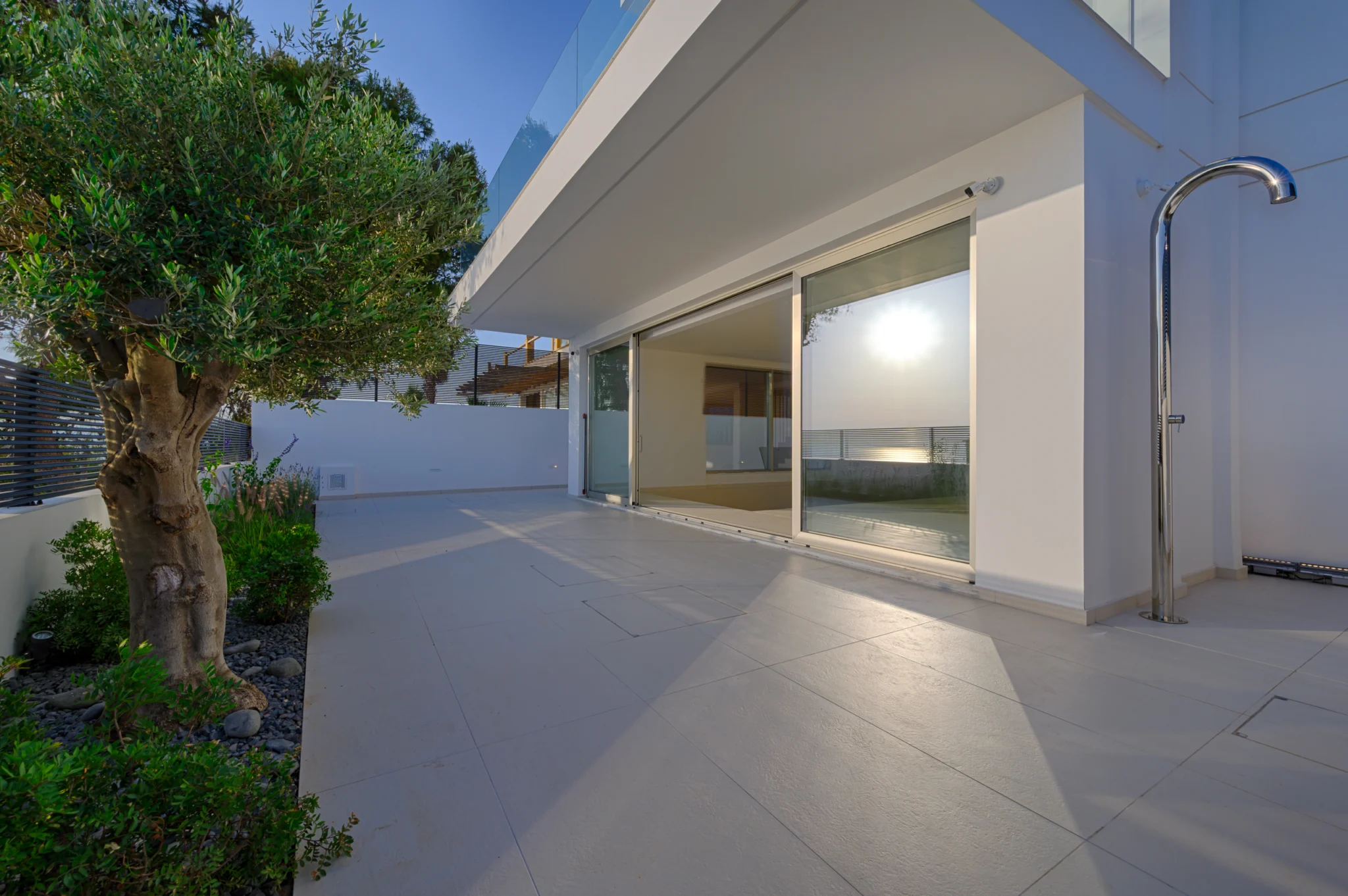 Terrace and olive tree reflected in sliding glass doors in evening light at Luxury Residence Blackstone.