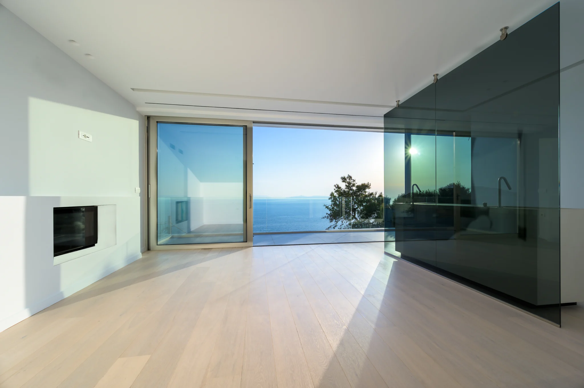 Sea-facing room with a glass partition and recessed fireplace in evening light at Luxury Residence Blackstone.