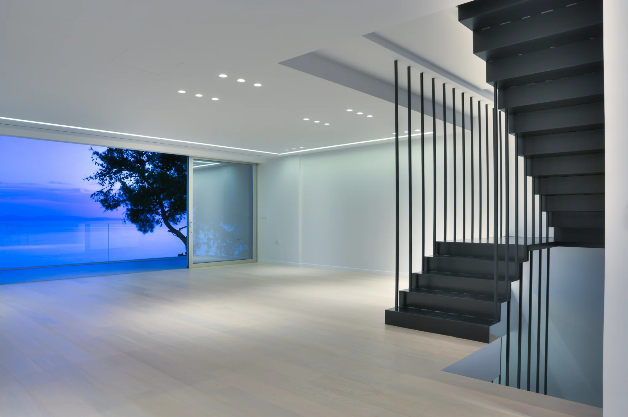 Wide sea-facing interior and black staircase at blue hour at Luxury Residence Blackstone.