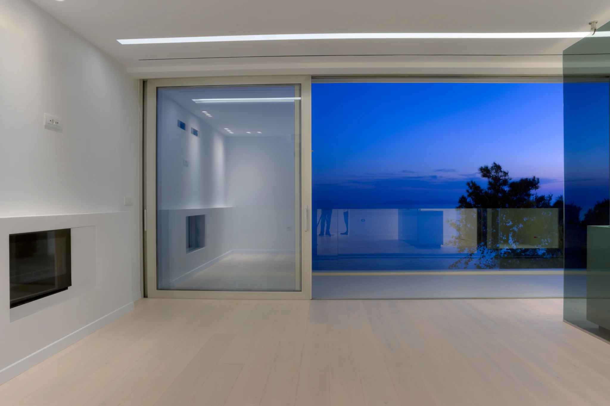 Recessed fireplace beside an open sliding door and illuminated terrace at twilight at Luxury Residence Blackstone.